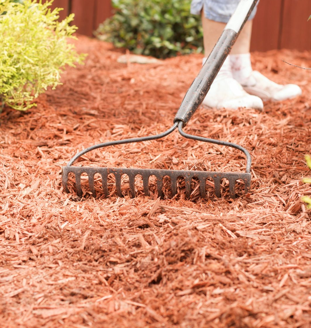 Dump truck unloading gravel onto a dirt surface under a bright blue sky.