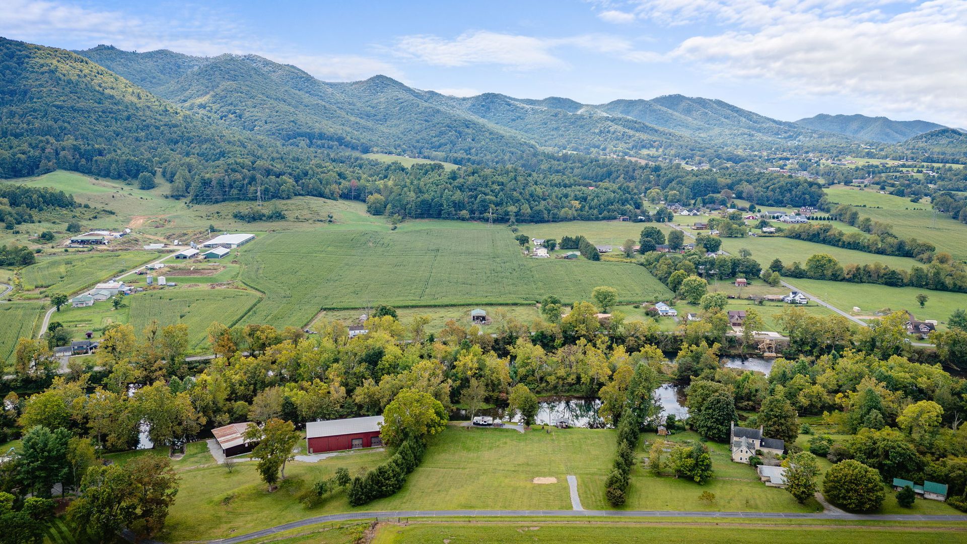 Rolling green hills and fields, with a small town nestled below mountains.