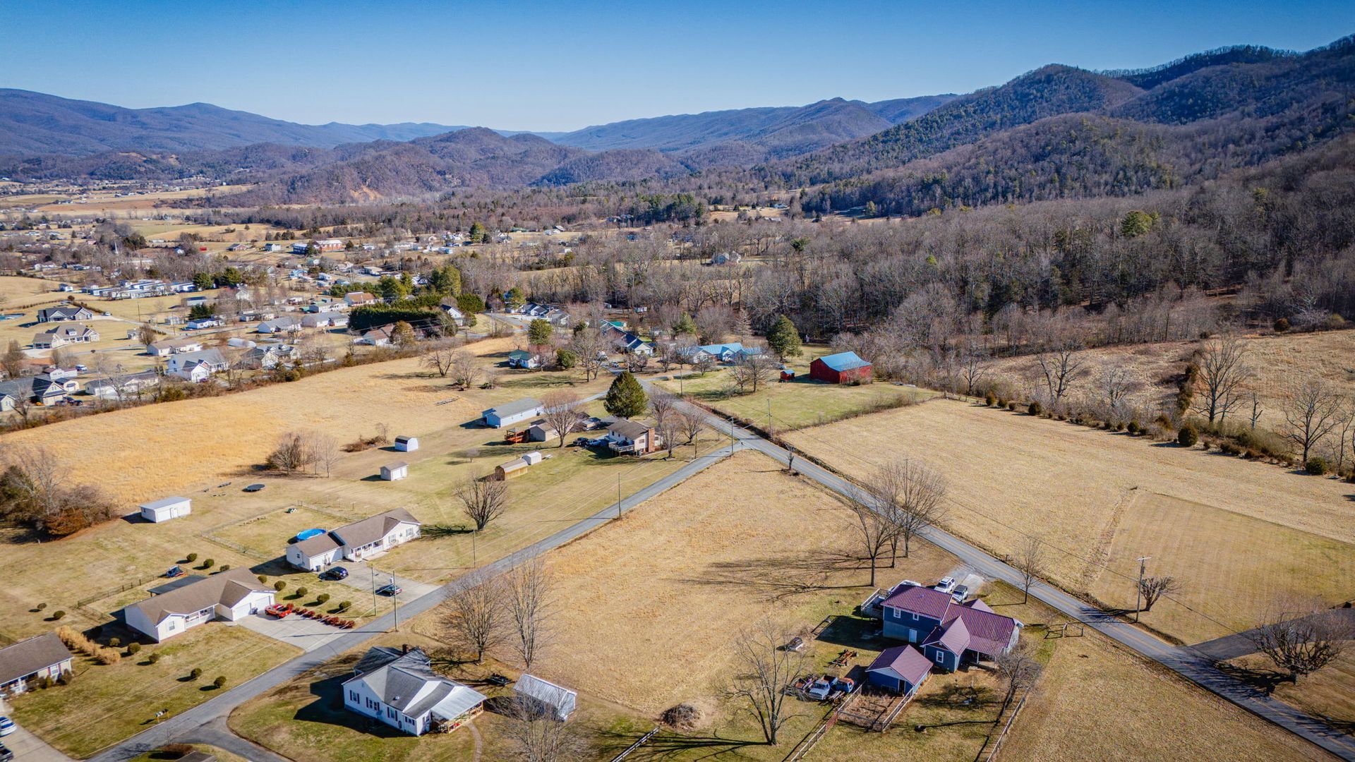 Aerial view of a rural landscape with a small town, fields, and mountains in the distance.