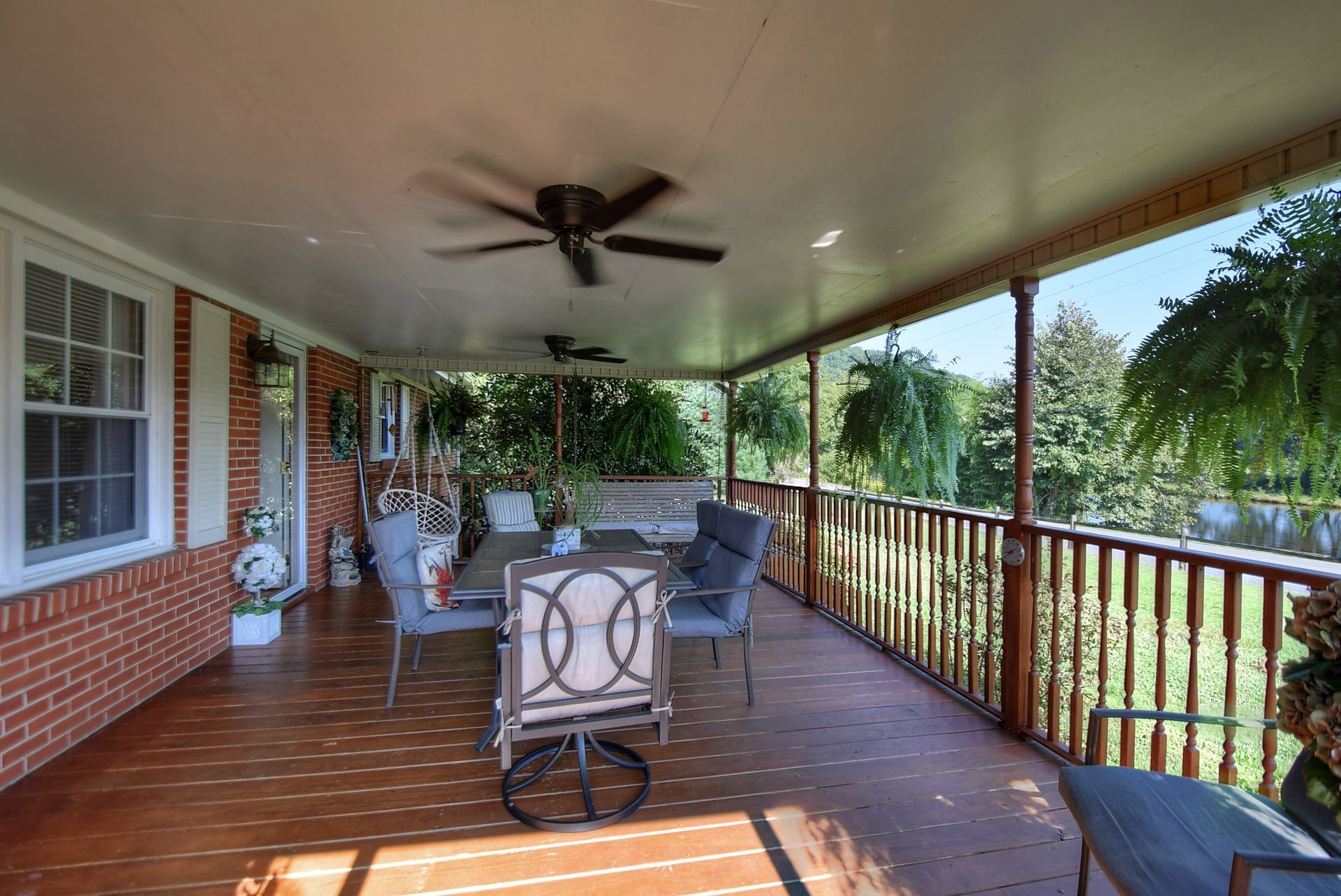 A large porch with a table and chairs and a ceiling fan.