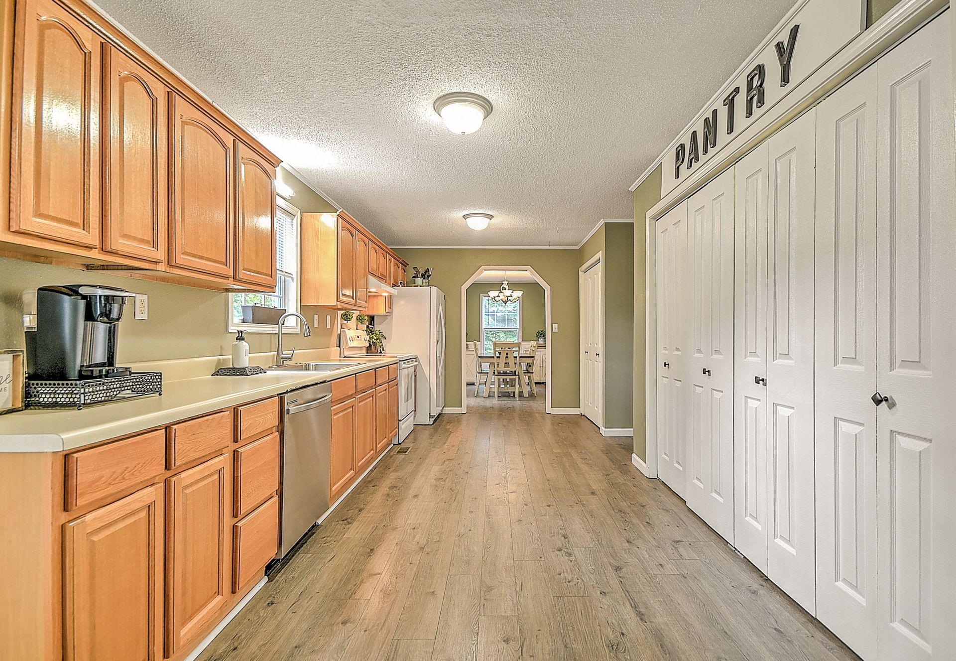 A kitchen with wooden cabinets and stainless steel appliances and a sign that says pantry on the wall.