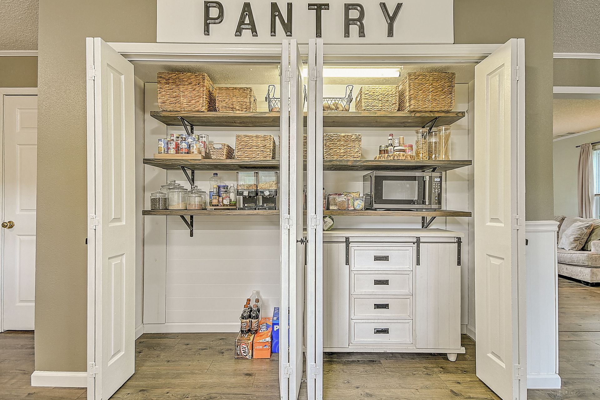 A pantry with shelves and drawers in a house with the doors open.
