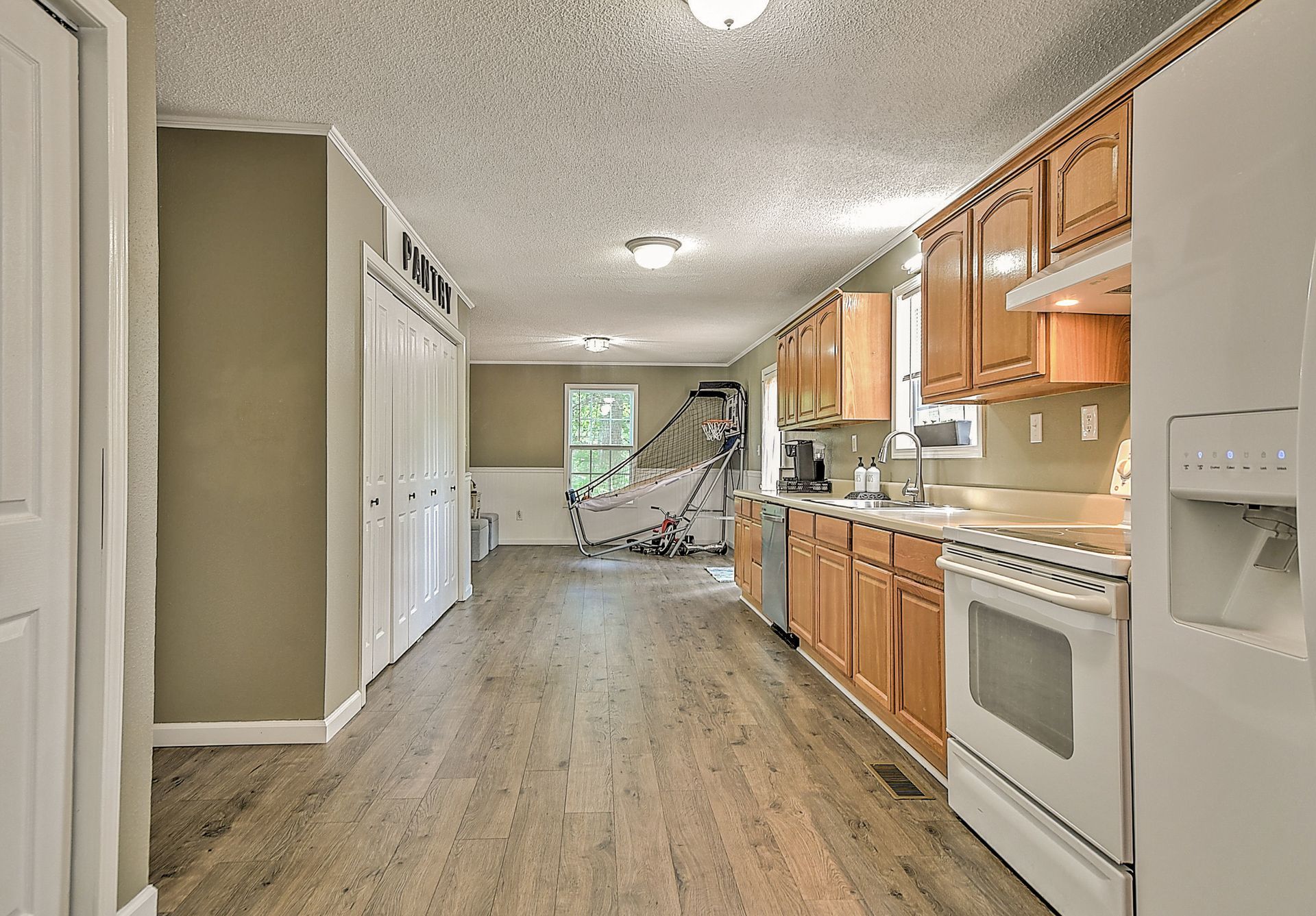 A kitchen with wooden cabinets , a stove , a refrigerator , and a dishwasher.