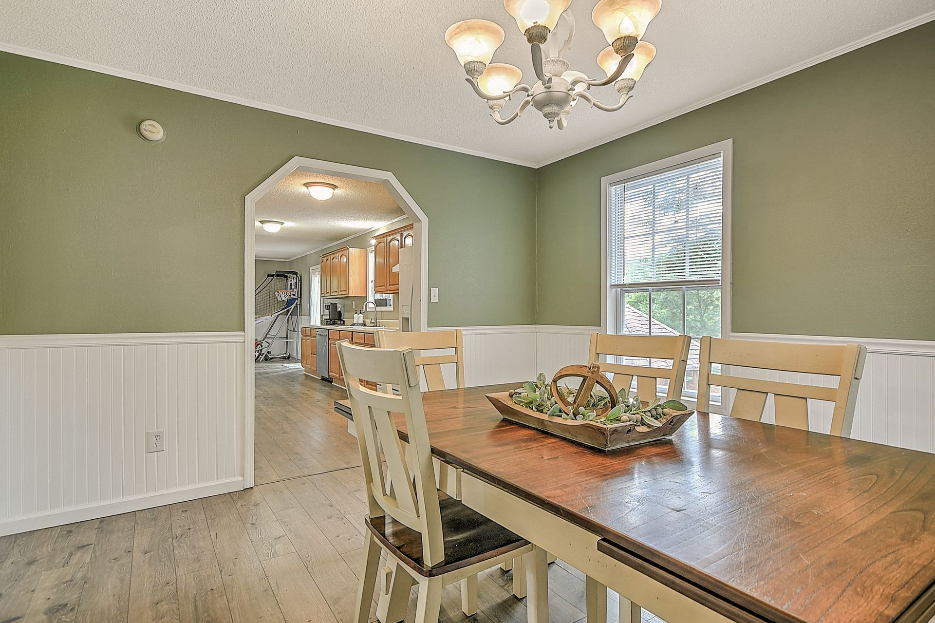 A dining room with a wooden table and chairs and a chandelier.