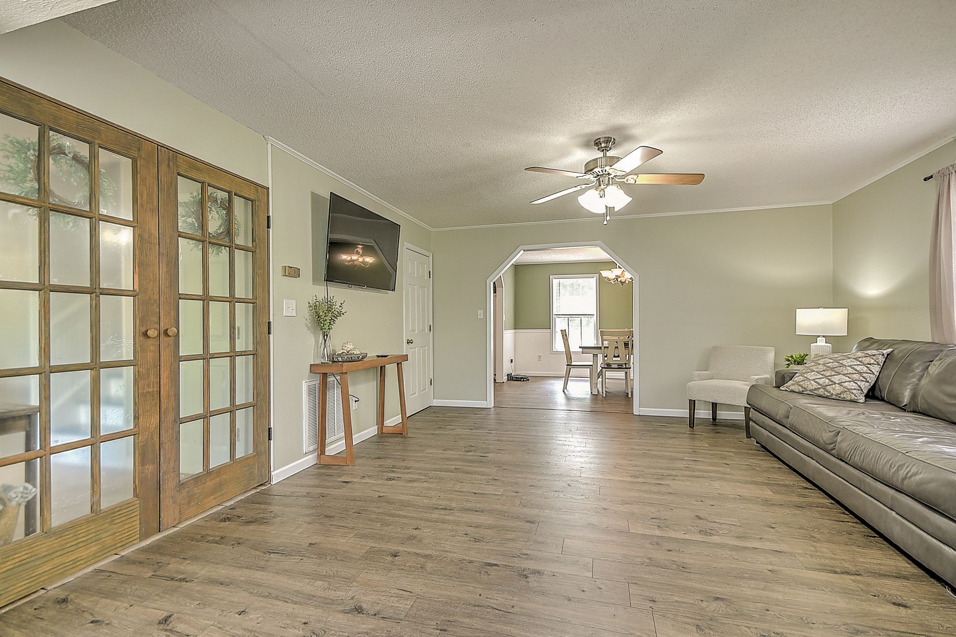 A living room with a couch , chairs , and a ceiling fan.