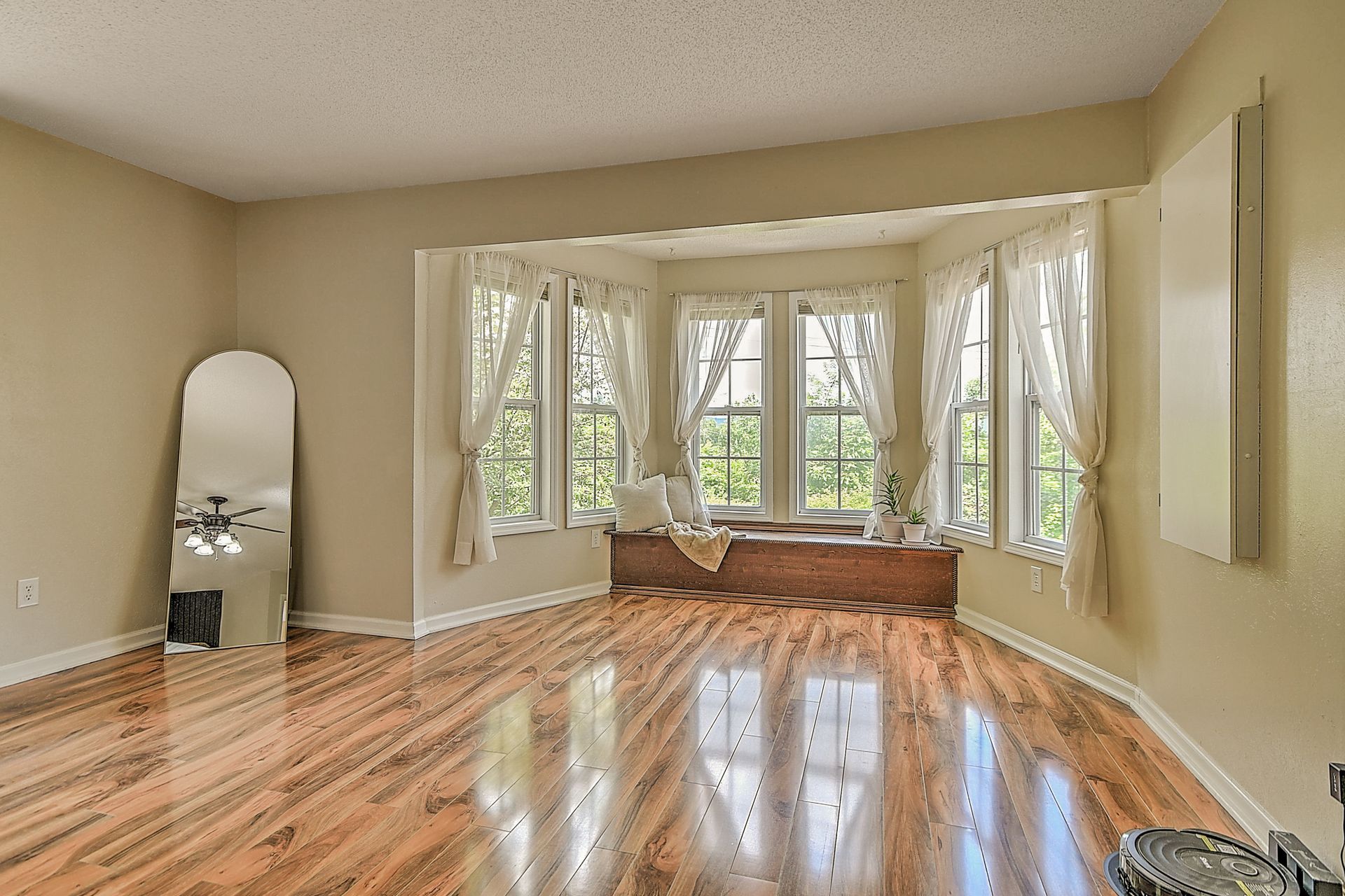An empty living room with hardwood floors and a large window