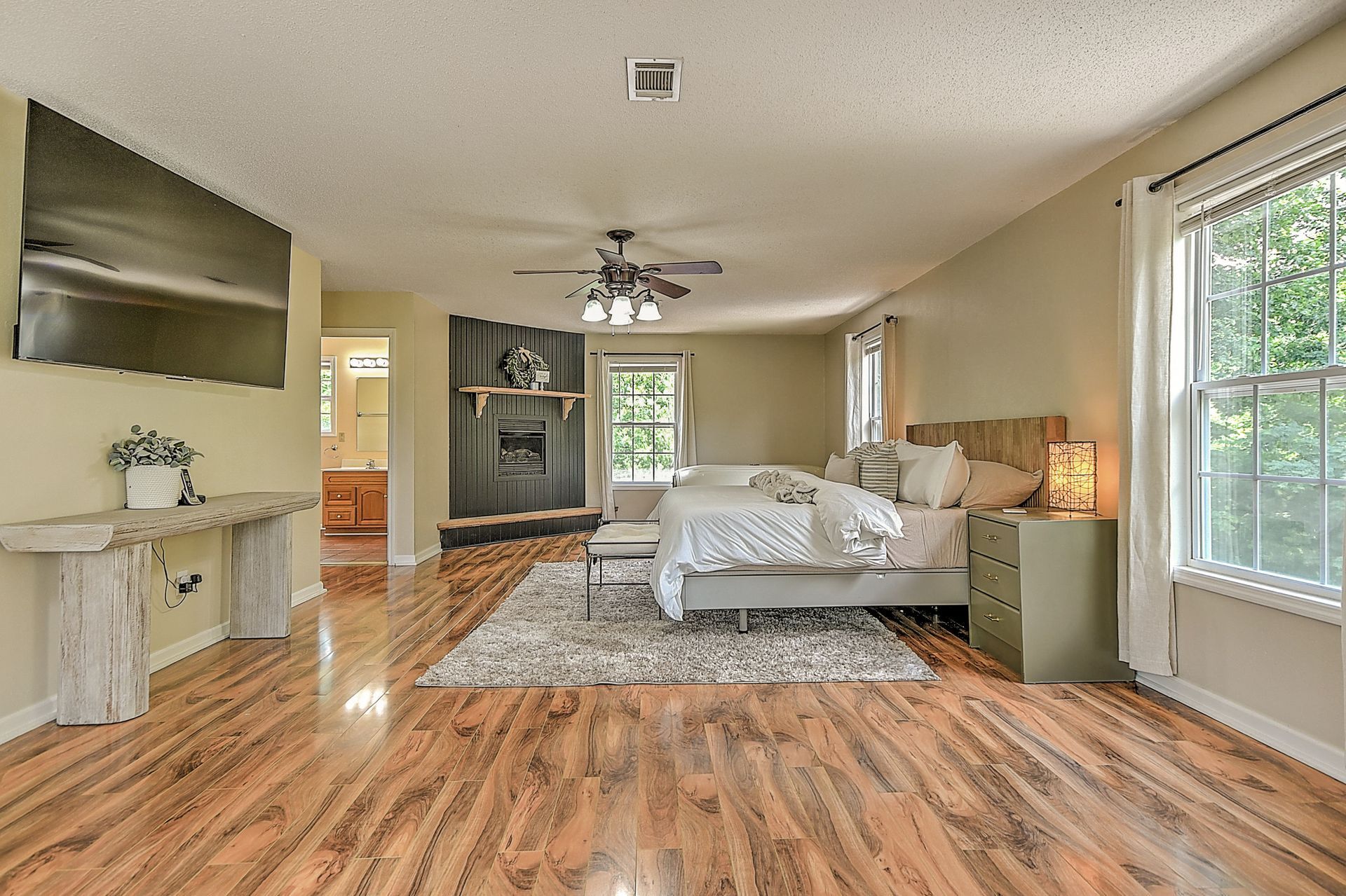 A large bedroom with hardwood floors and a fireplace.