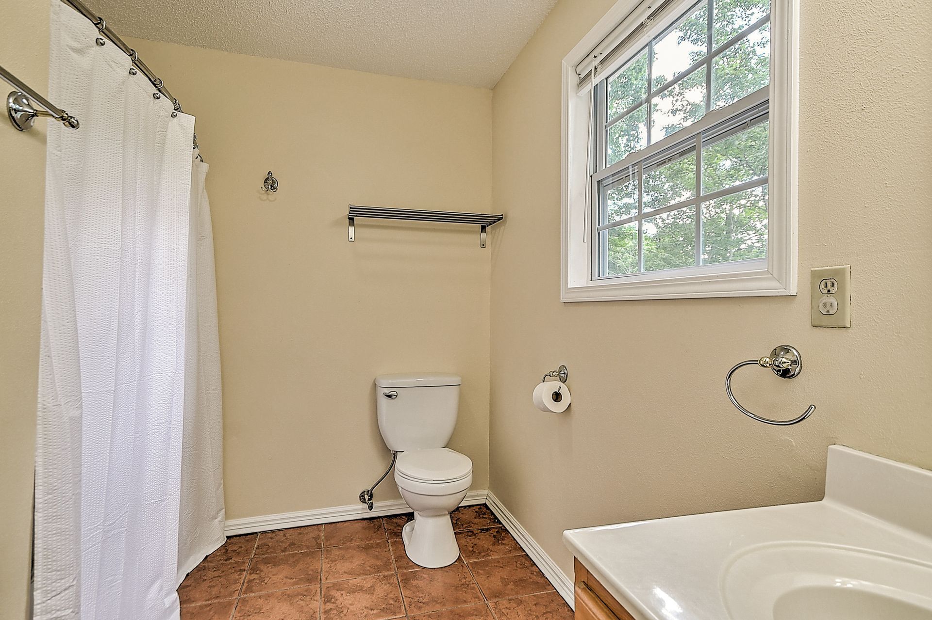 A bathroom with a toilet , sink and window