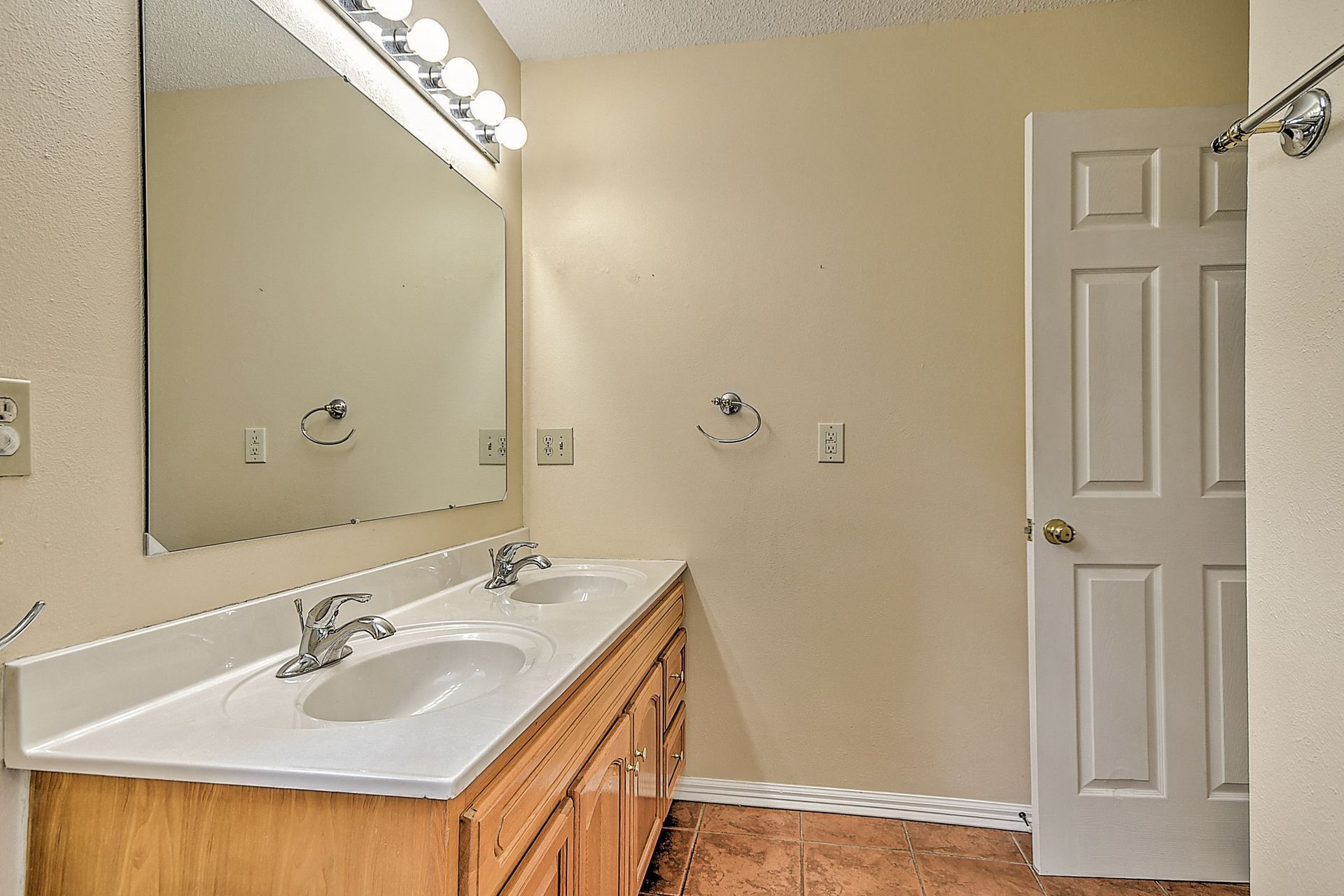 A bathroom with two sinks , a mirror and a door.