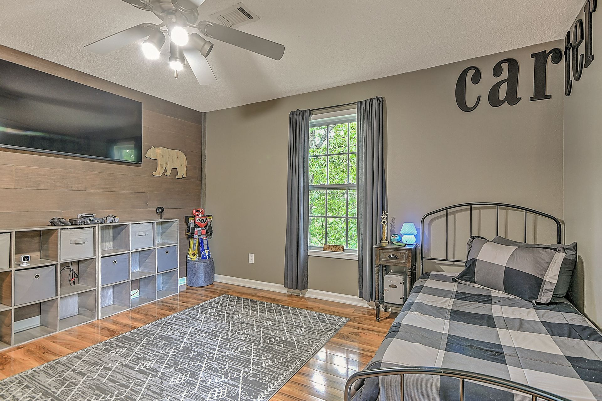 A bedroom with a bed , television , and a ceiling fan.