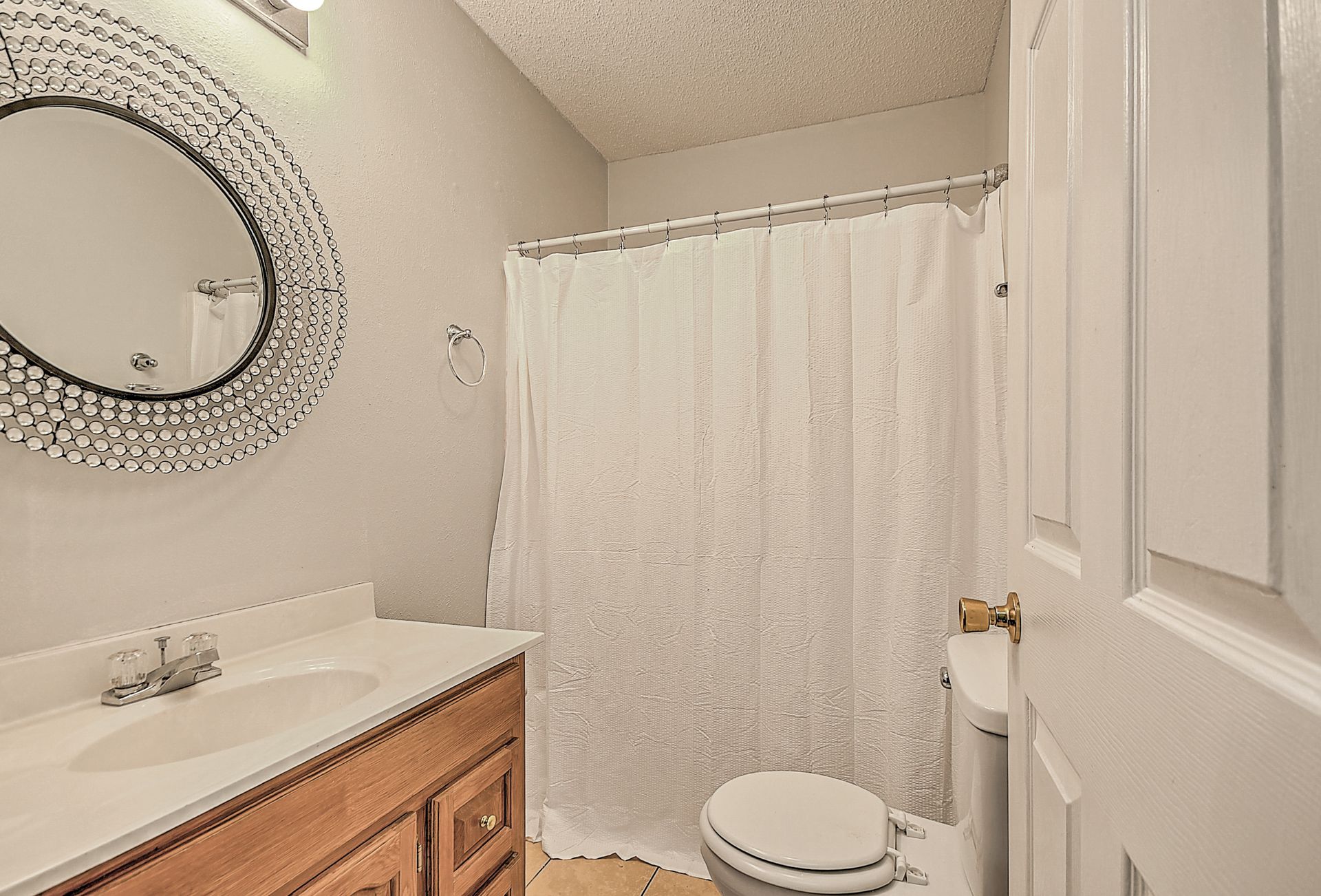 A bathroom with a toilet , sink , mirror and shower curtain.