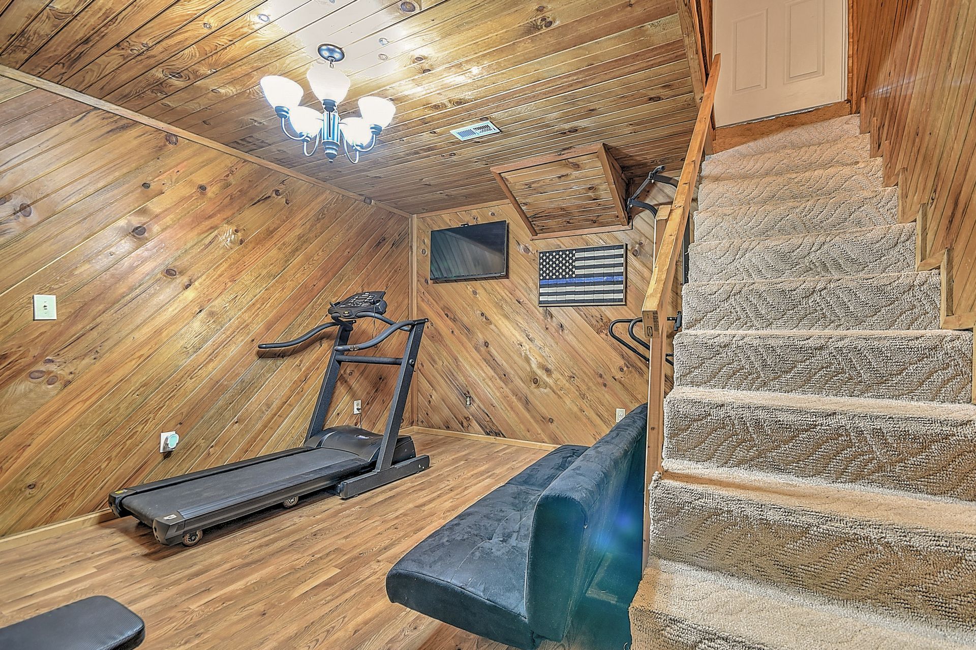 A treadmill is sitting in a room next to stairs.