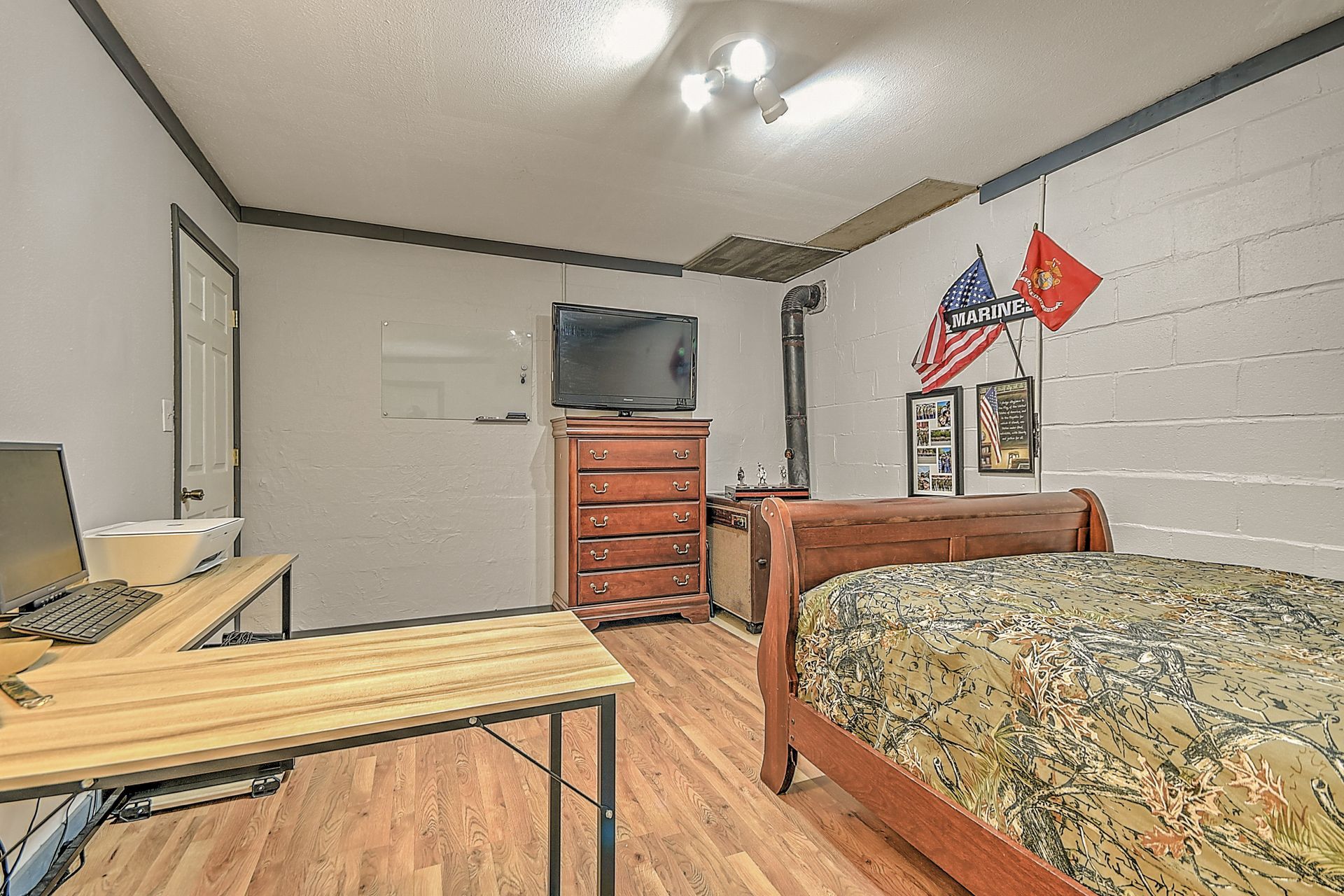 A bedroom with a bed , desk , television and dresser.