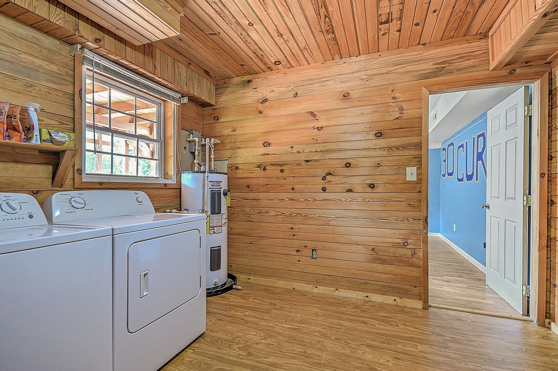 A laundry room in a log cabin with a washer and dryer.