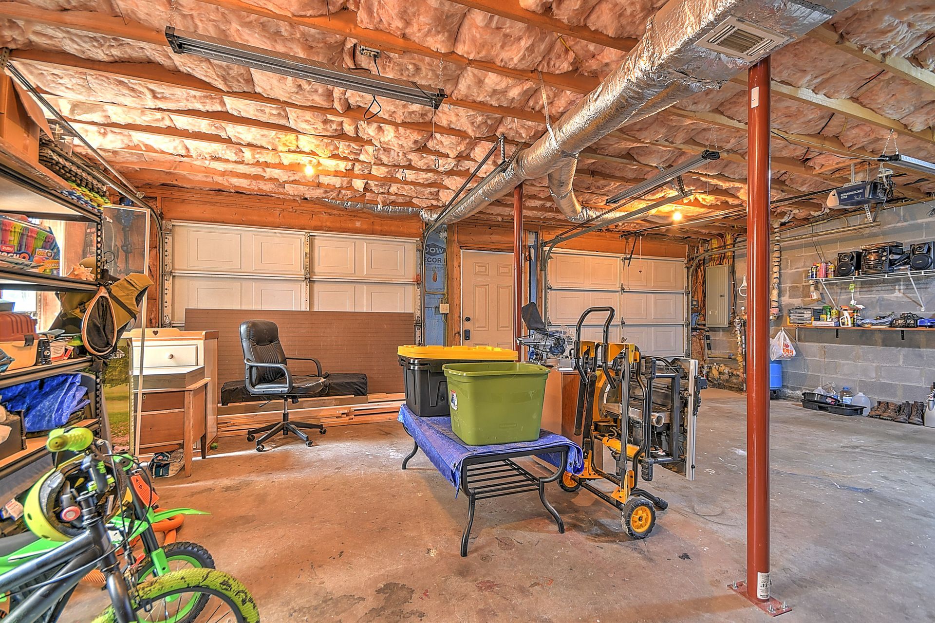 A garage filled with lots of bikes , tools , and other items.