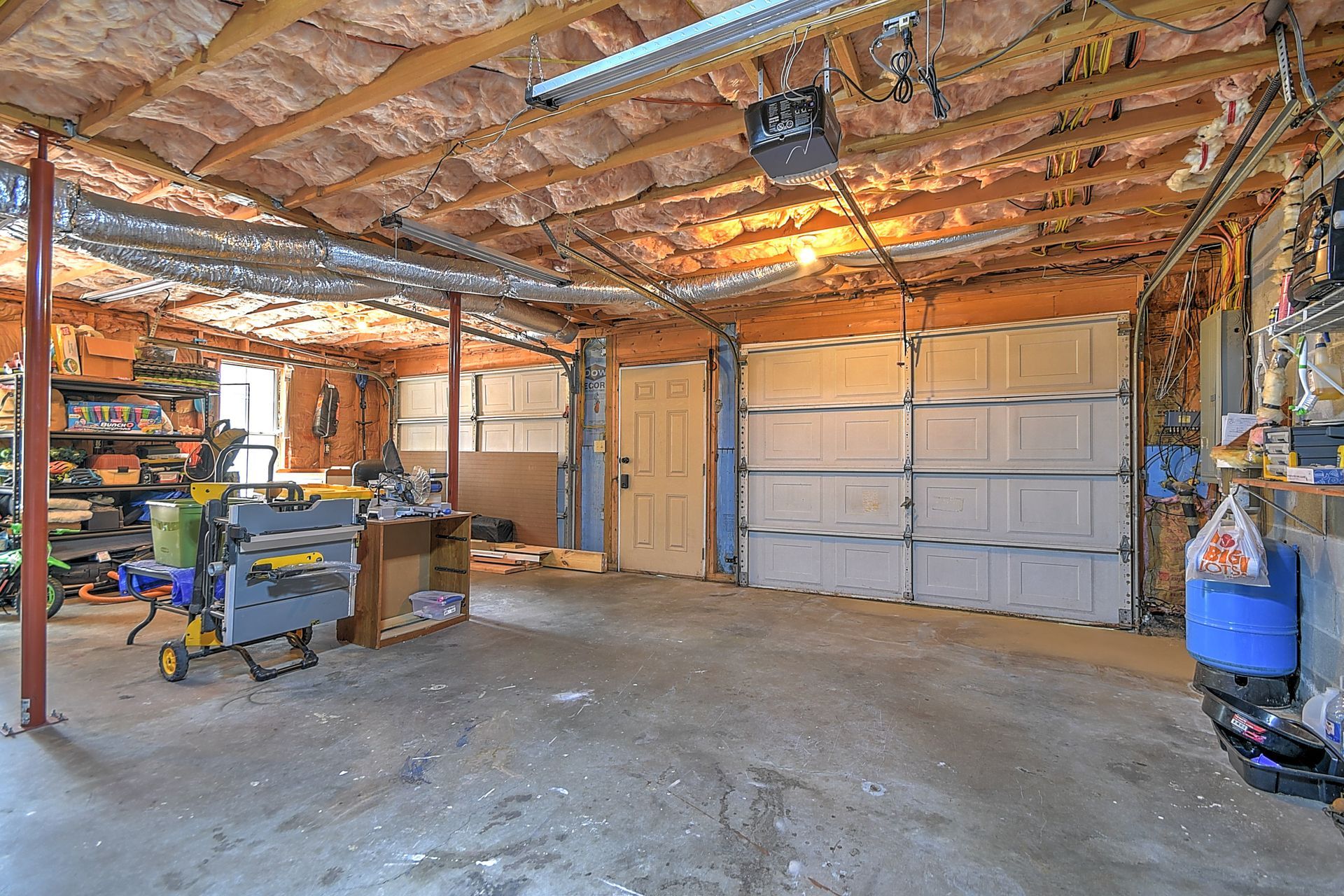 A garage with a garage door and a lot of tools in it.