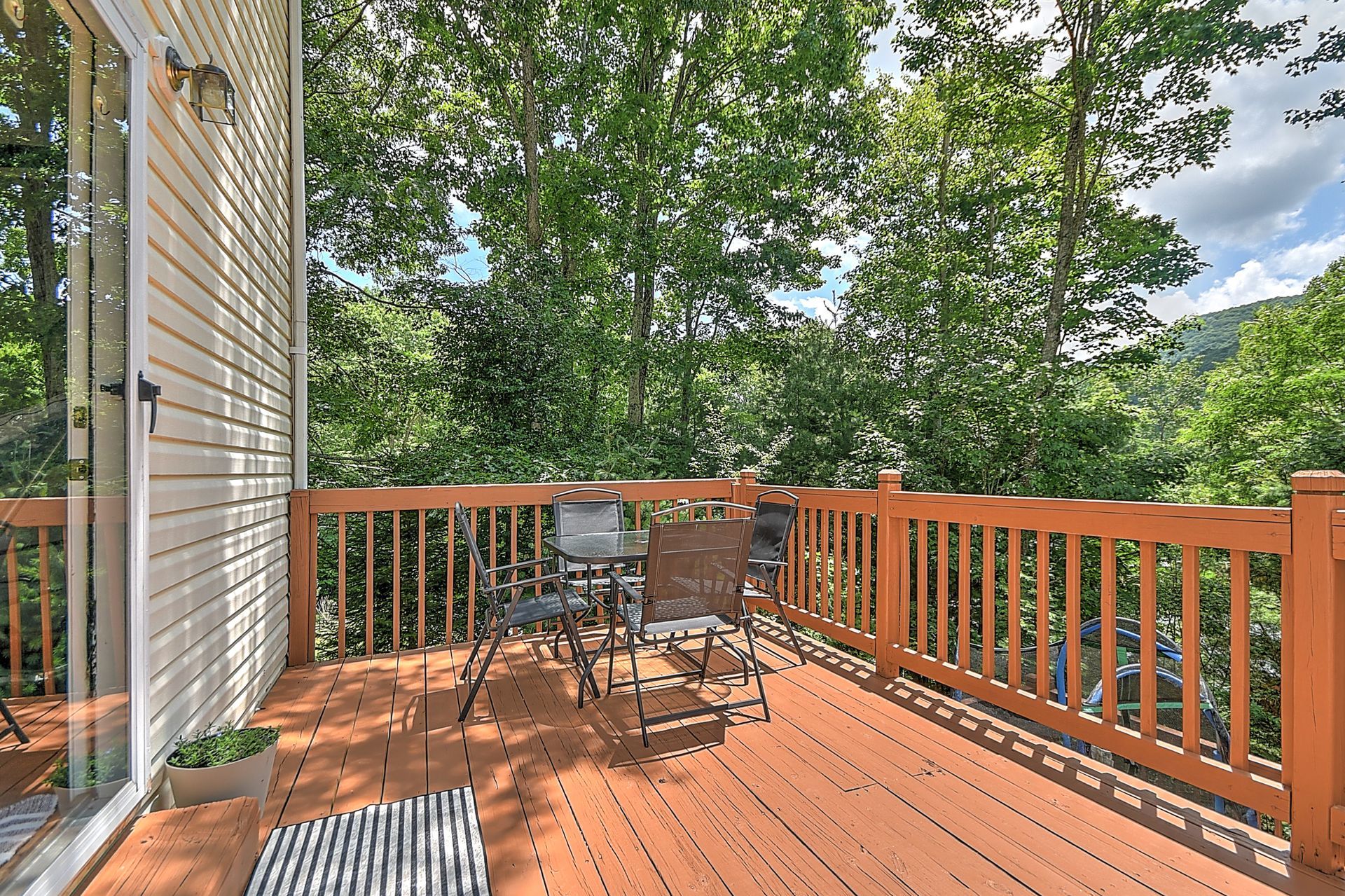 A wooden deck with a table and chairs on it in front of a house.