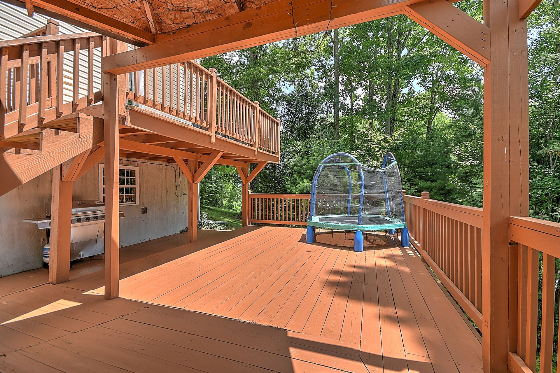 A large wooden deck with a trampoline on it