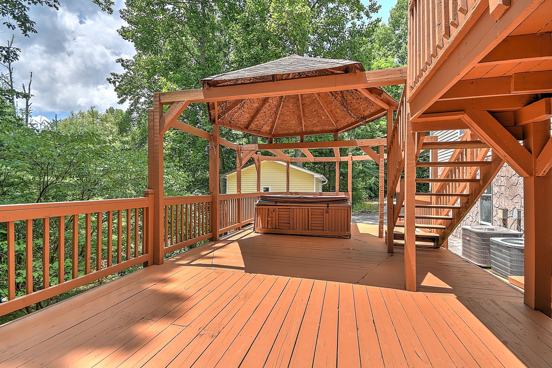 A wooden deck with a gazebo and stairs