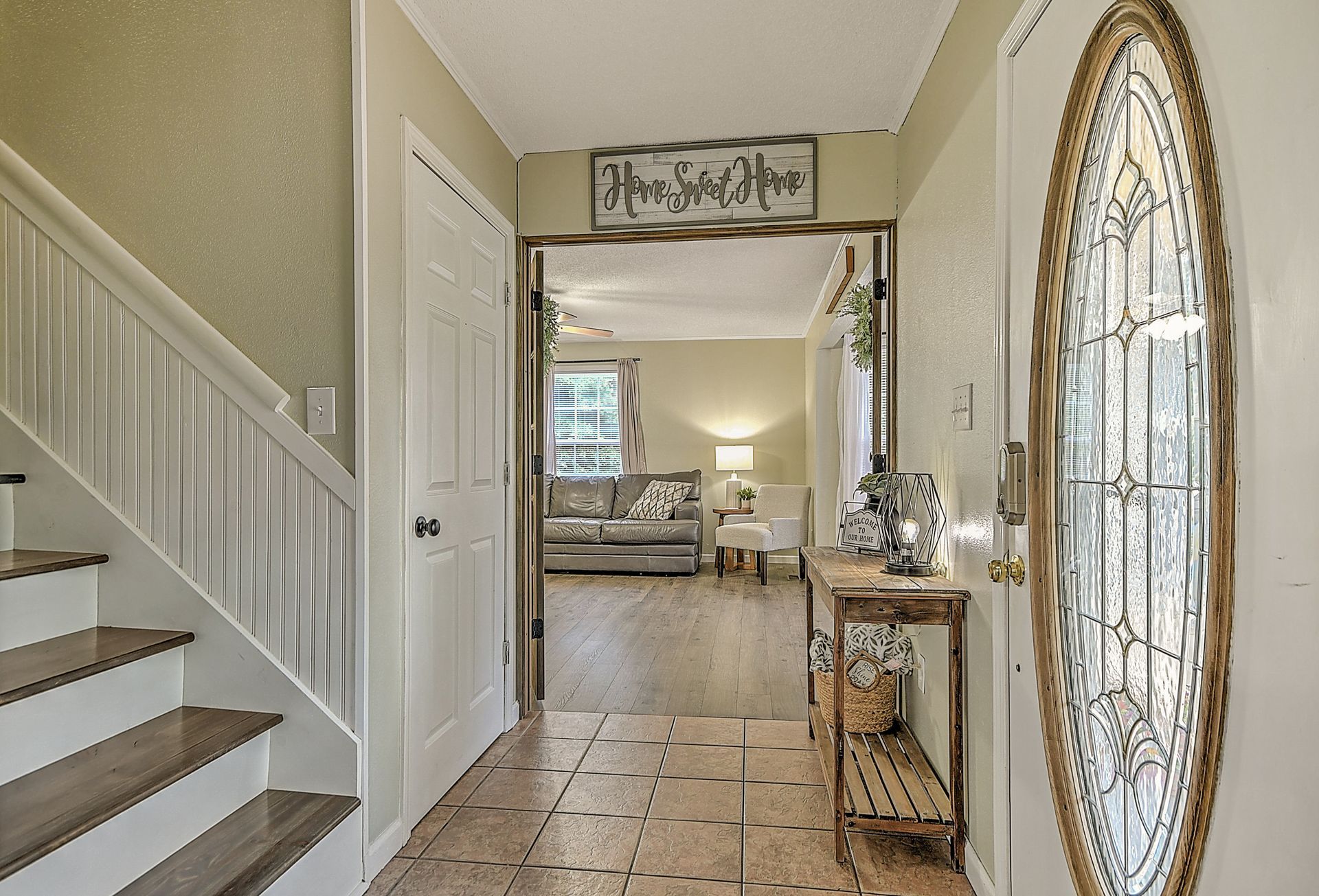 A hallway with stairs and a stained glass door leading to a living room.