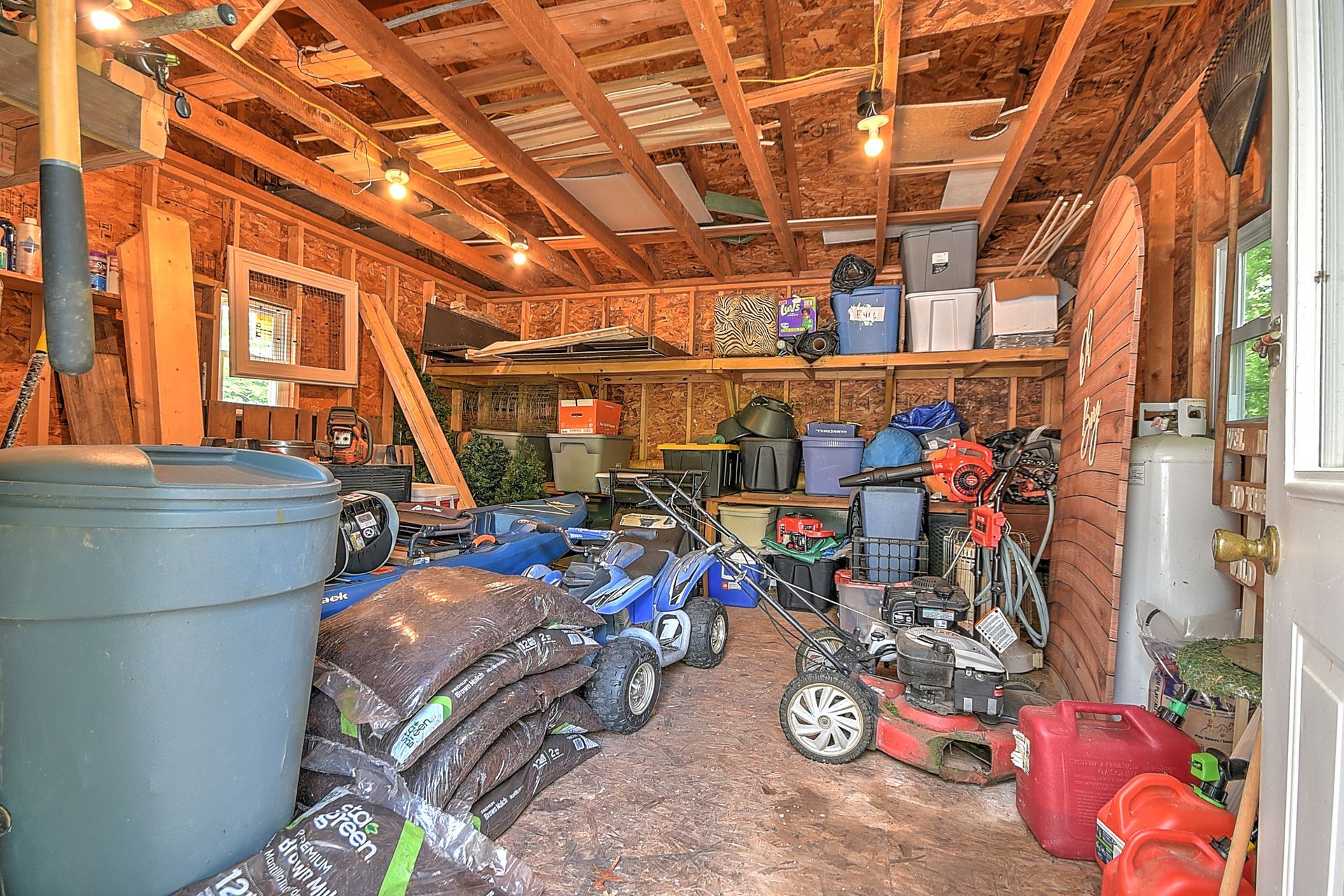 A garage filled with lots of tools and lawn mowers.