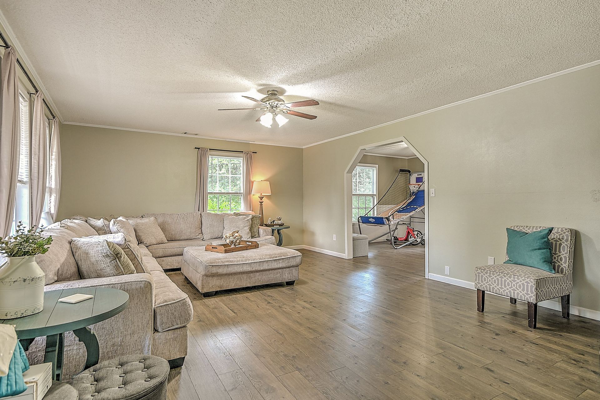 A living room with a couch , chair , table and ceiling fan.