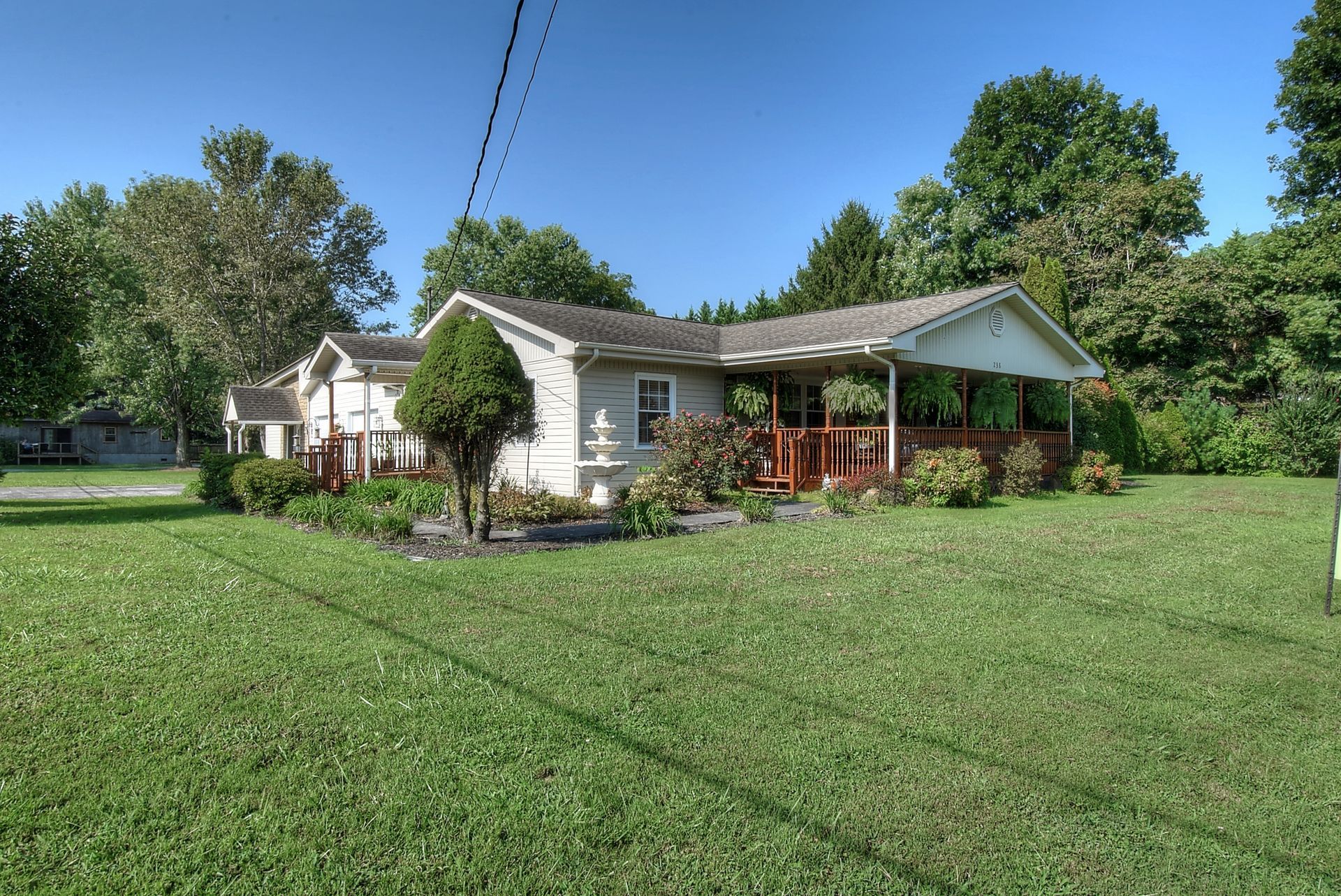 A white house with a porch in the middle of a lush green field