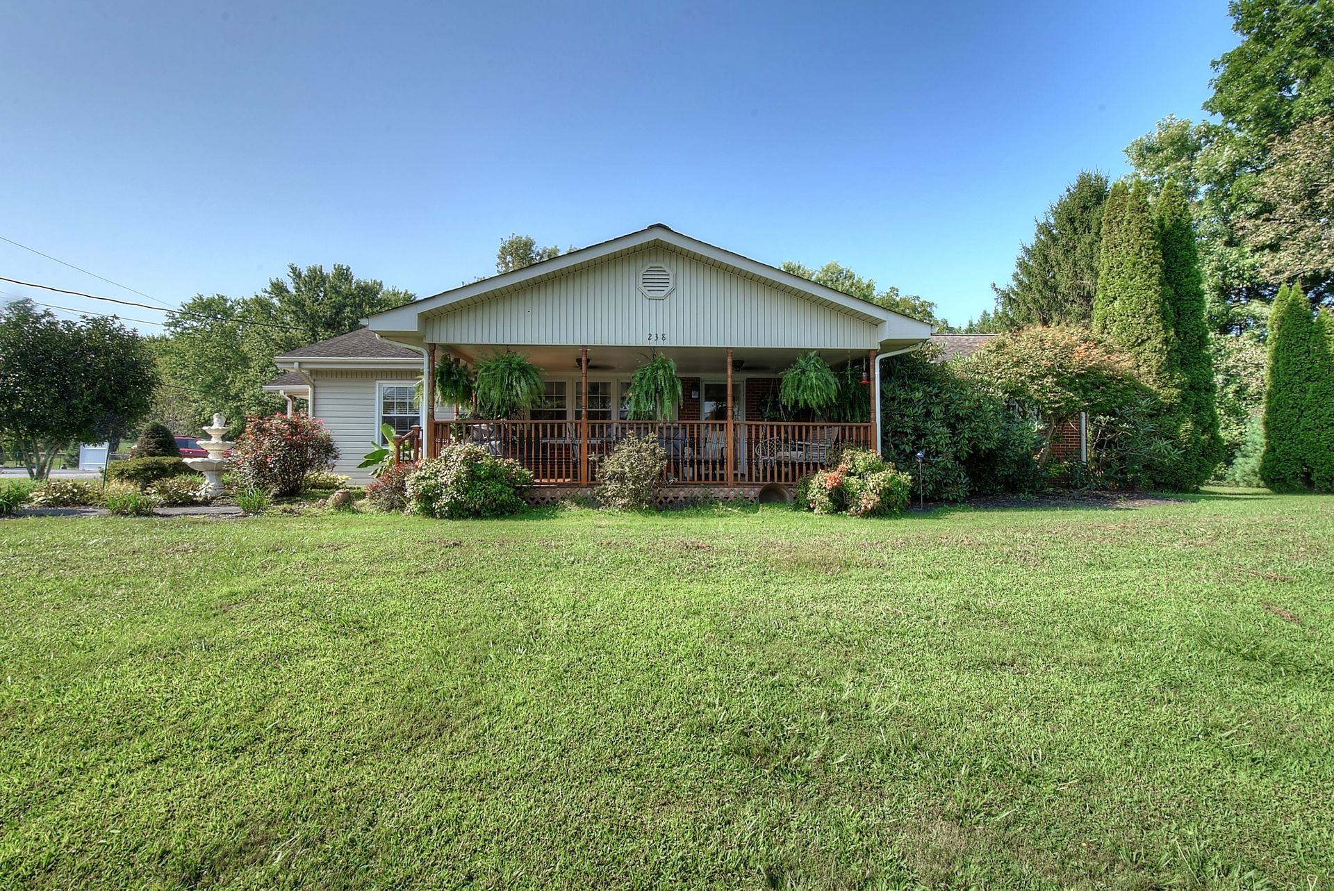 A house with a porch and a large lawn in front of it