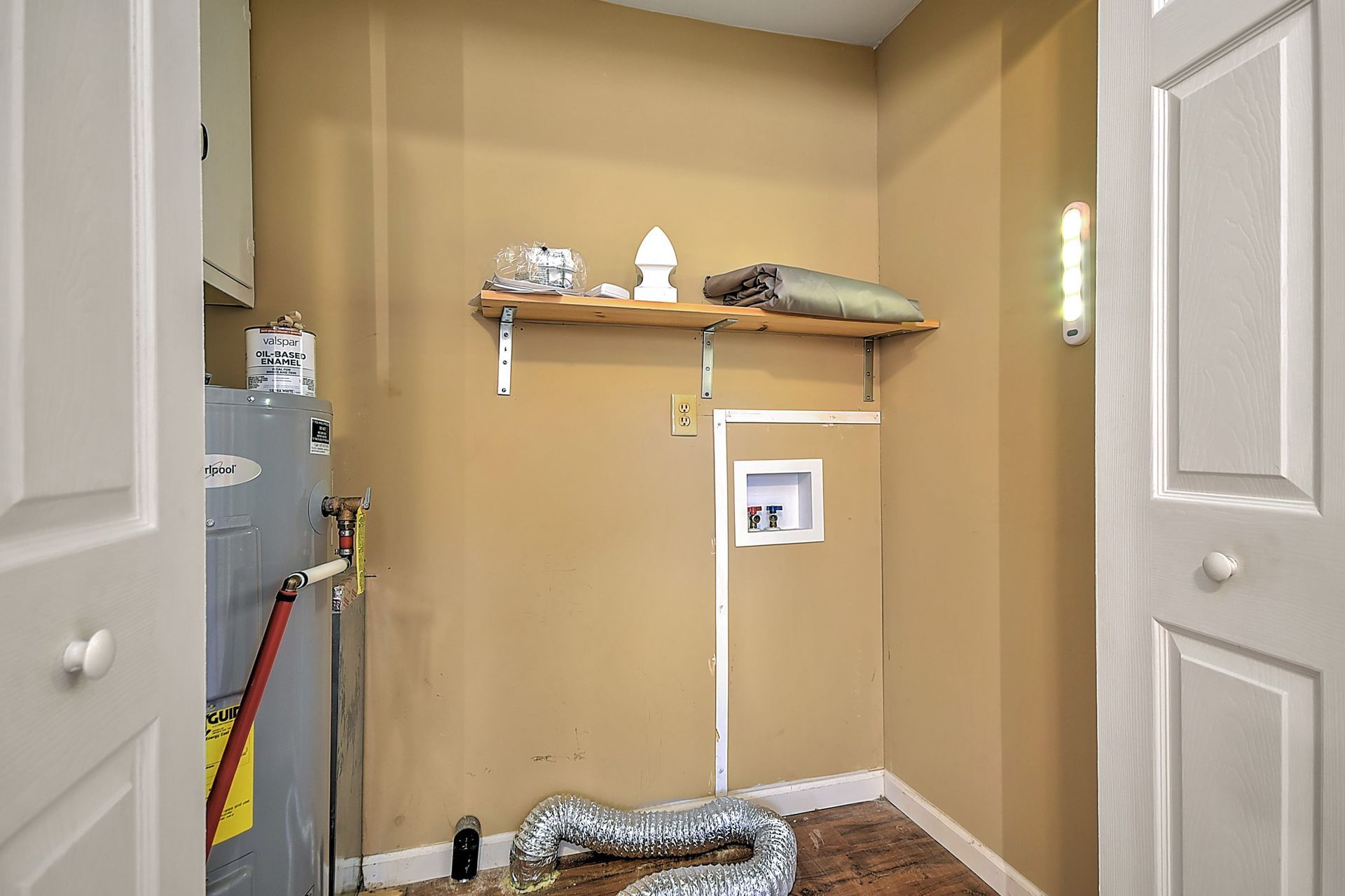 Laundry room with water heater, shelf, dryer vent, and electrical outlet.