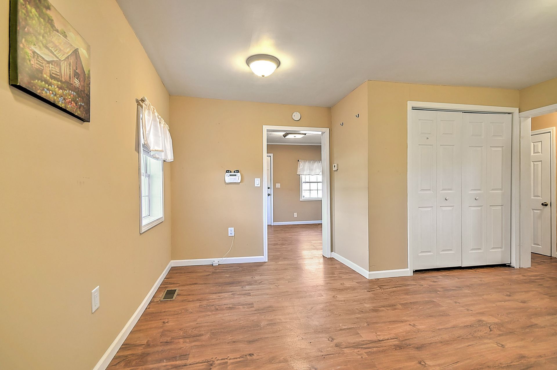 Interior of a home with light brown walls, wood-look flooring, and a closet.