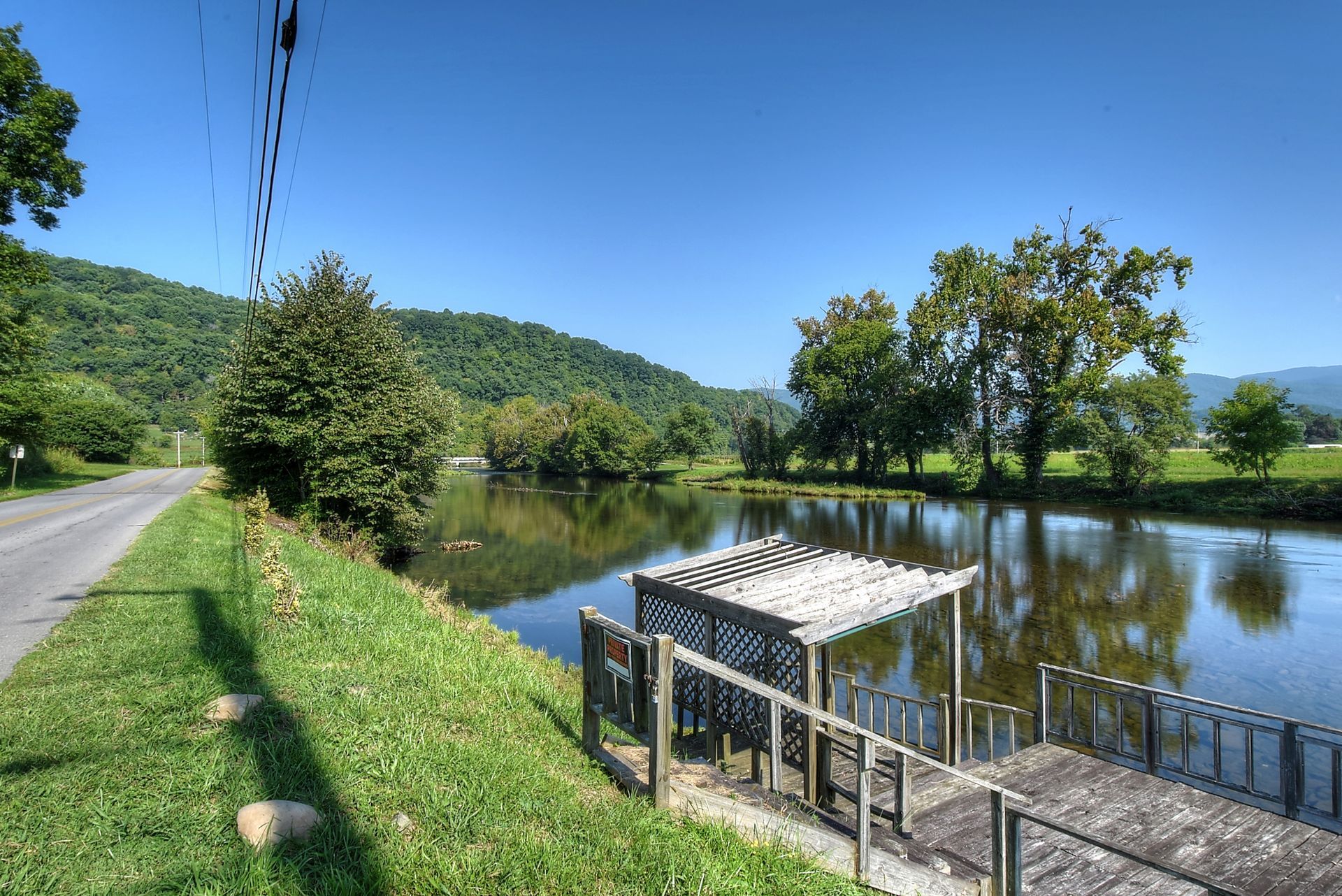 A dock with a pergola overlooking a lake with mountains in the background