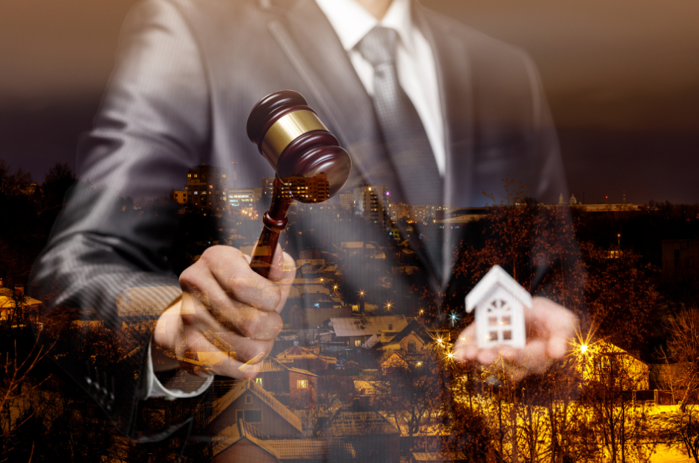 A man in a suit is holding a wooden gavel and a small house.
