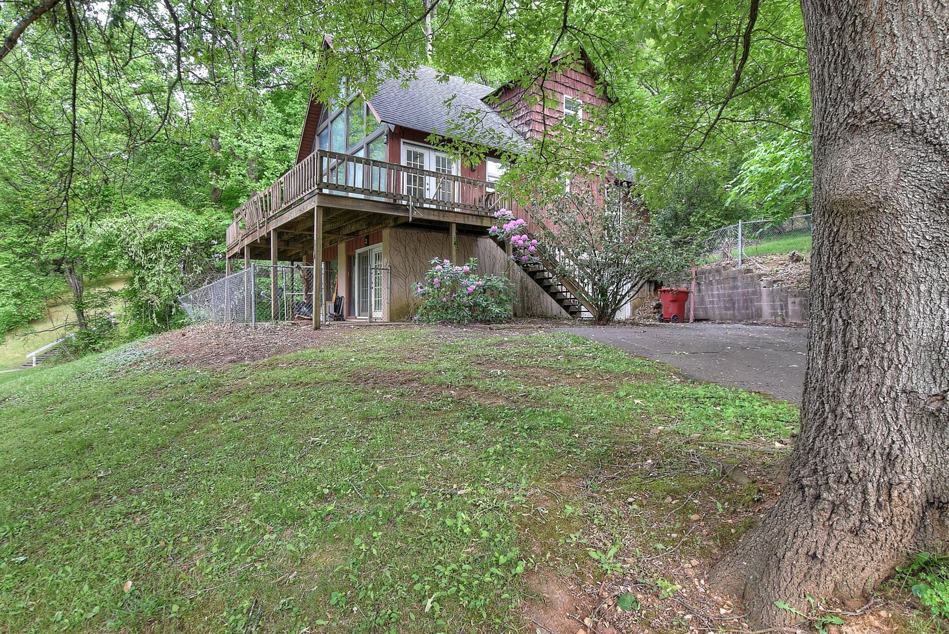 A large house with a large deck is surrounded by trees and grass.