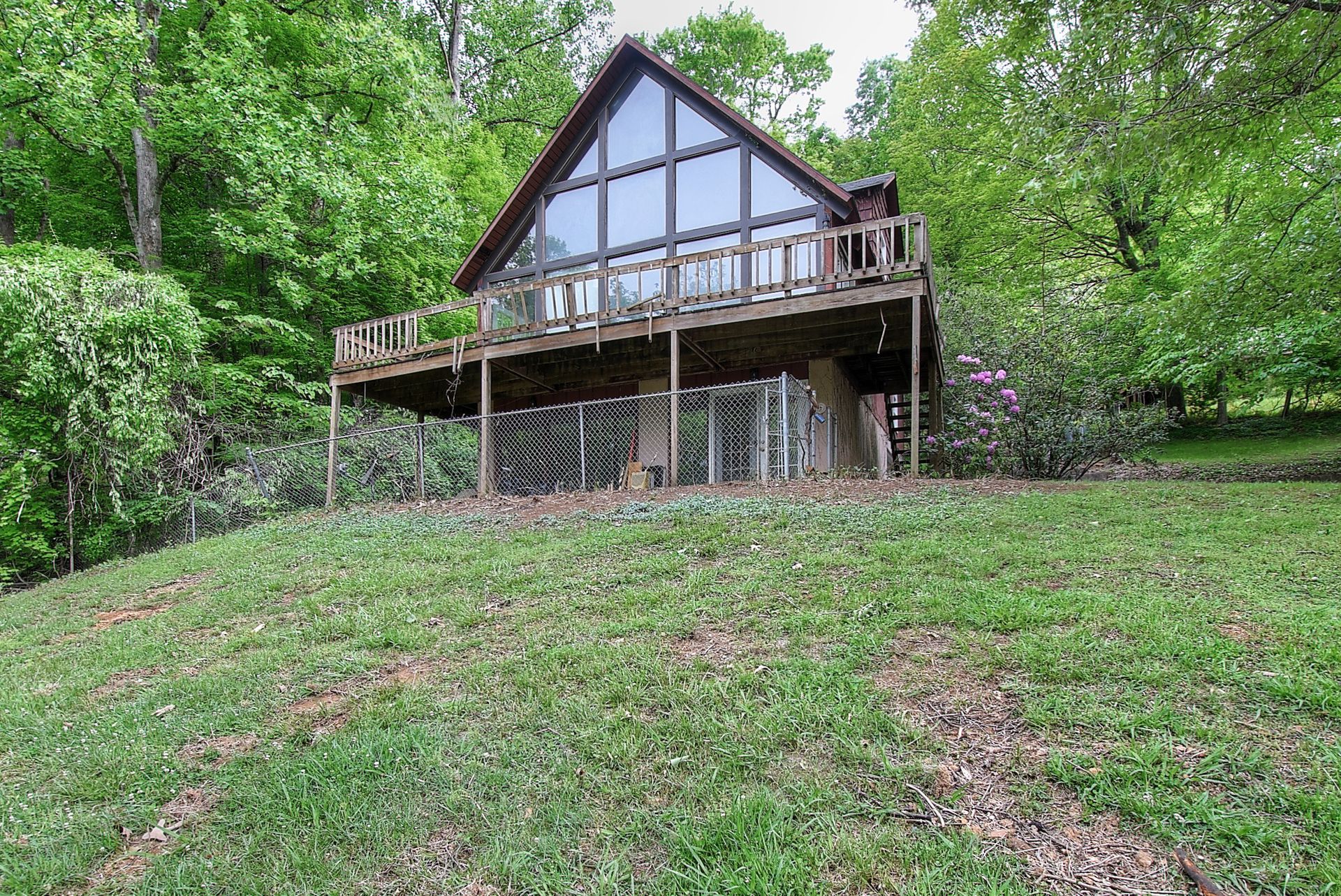 A cabin is sitting on top of a grassy hill in the middle of a forest.