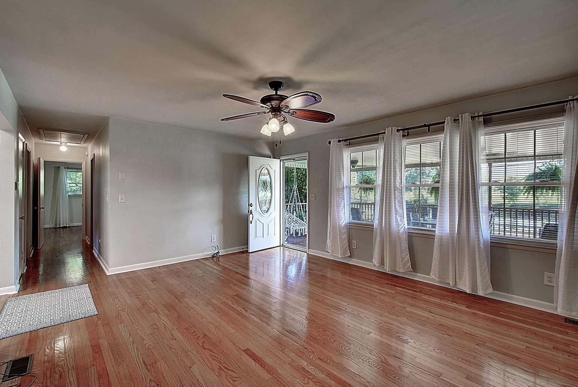 An empty living room with hardwood floors and a ceiling fan.