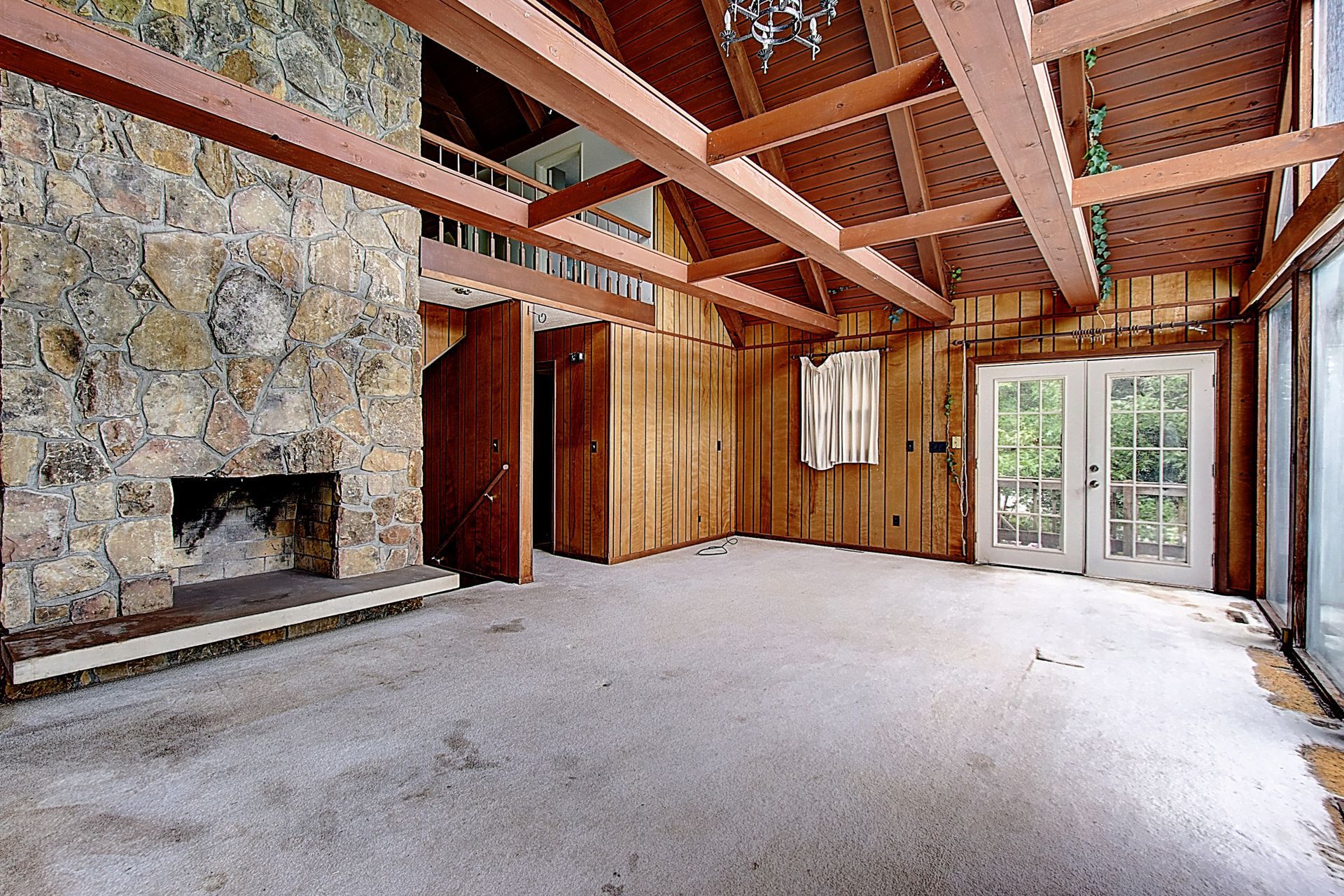 An empty room with a stone fireplace and wooden beams