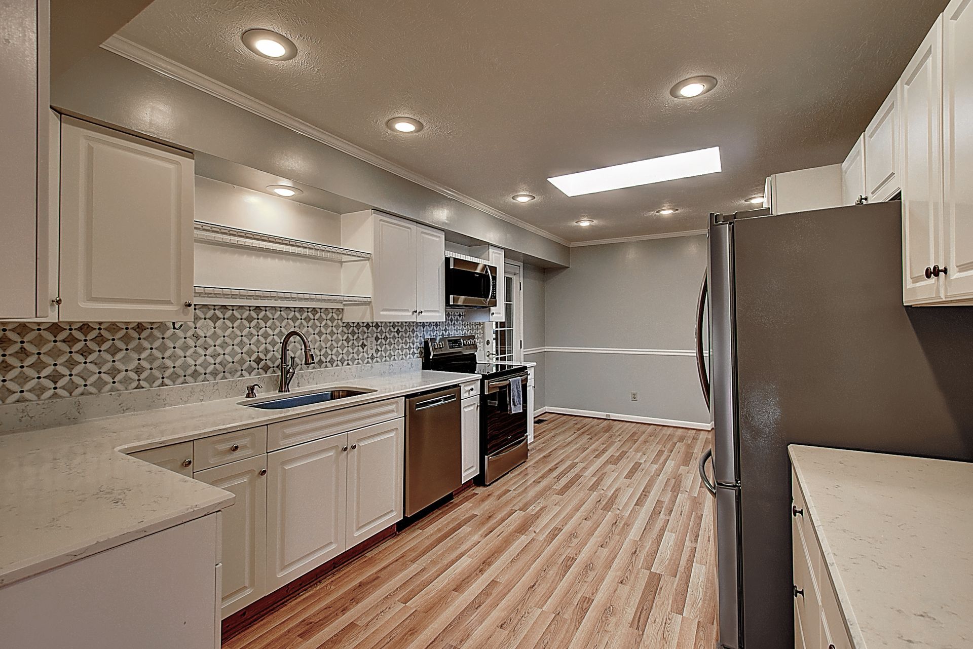 A kitchen with white cabinets , stainless steel appliances and hardwood floors.