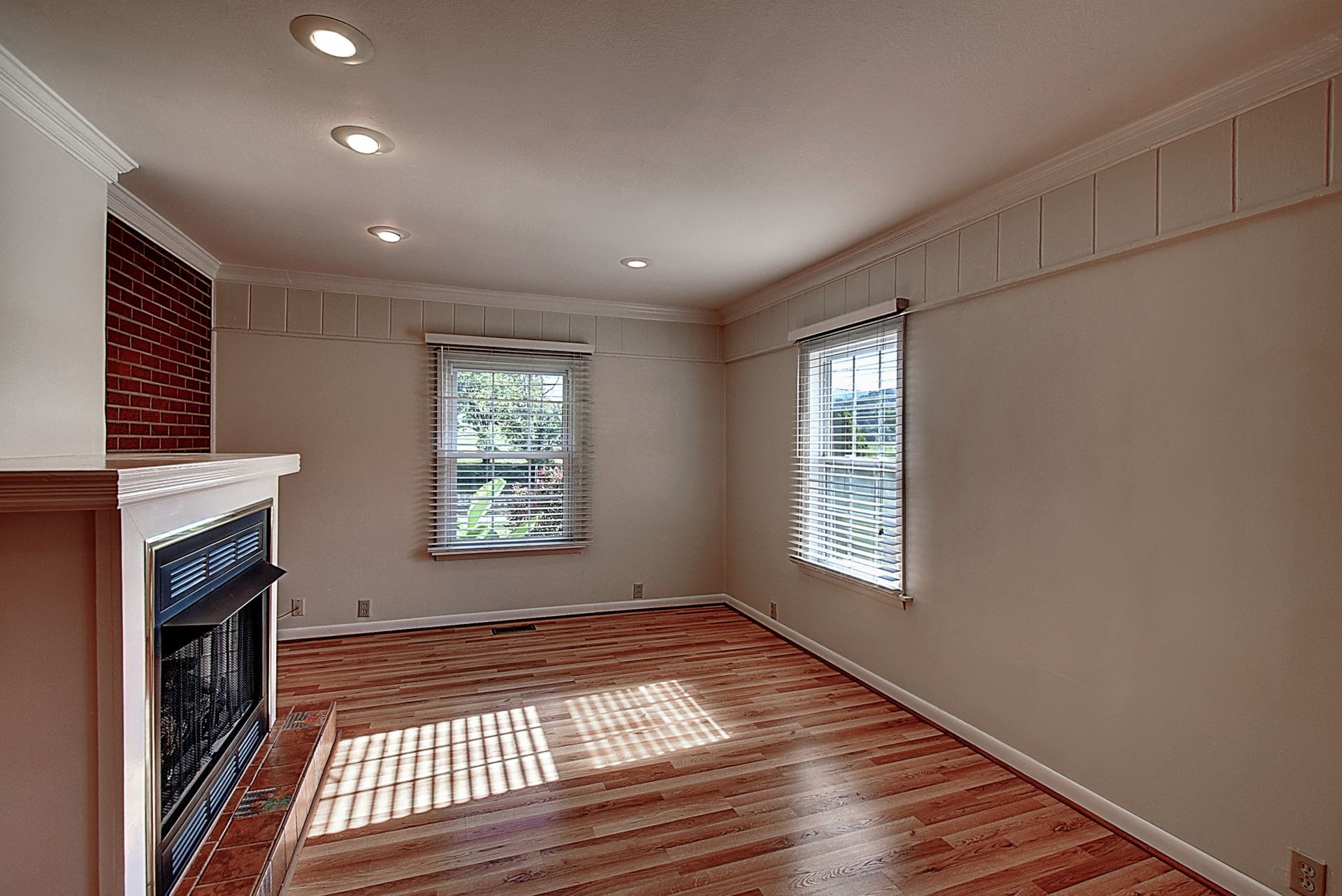 An empty living room with hardwood floors and a fireplace