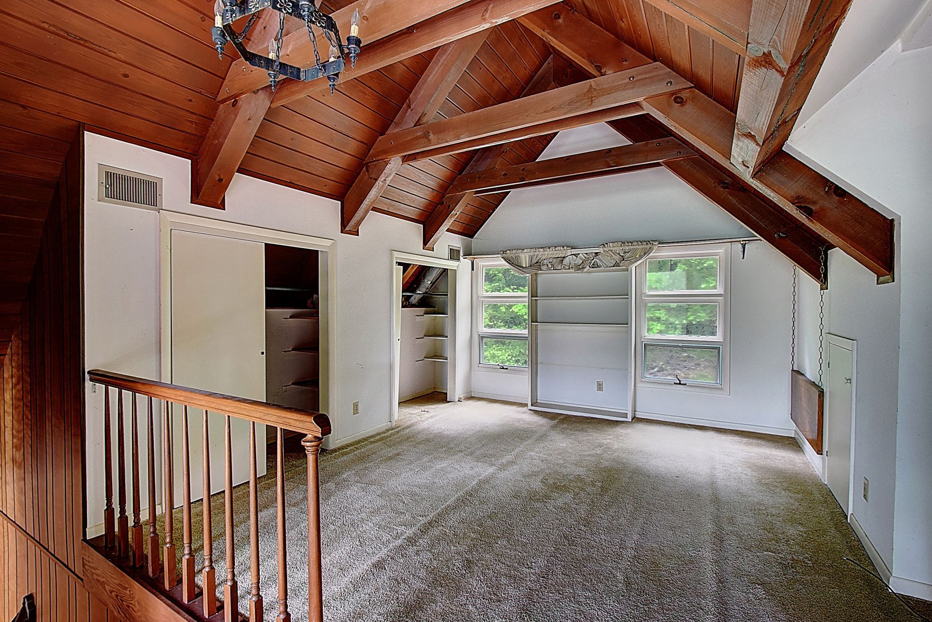 An empty room with a wooden ceiling and stairs