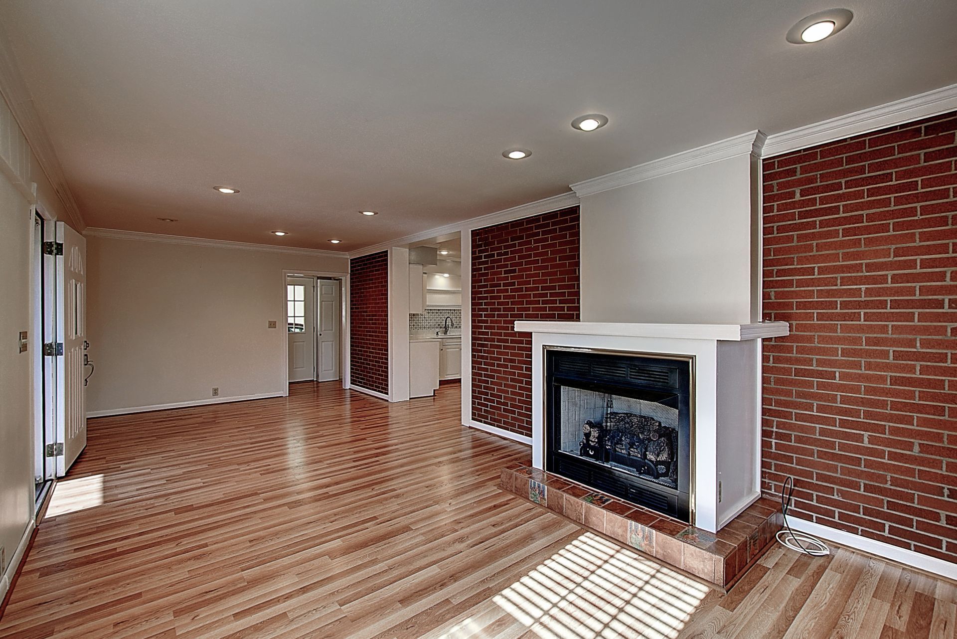 An empty living room with hardwood floors and a fireplace