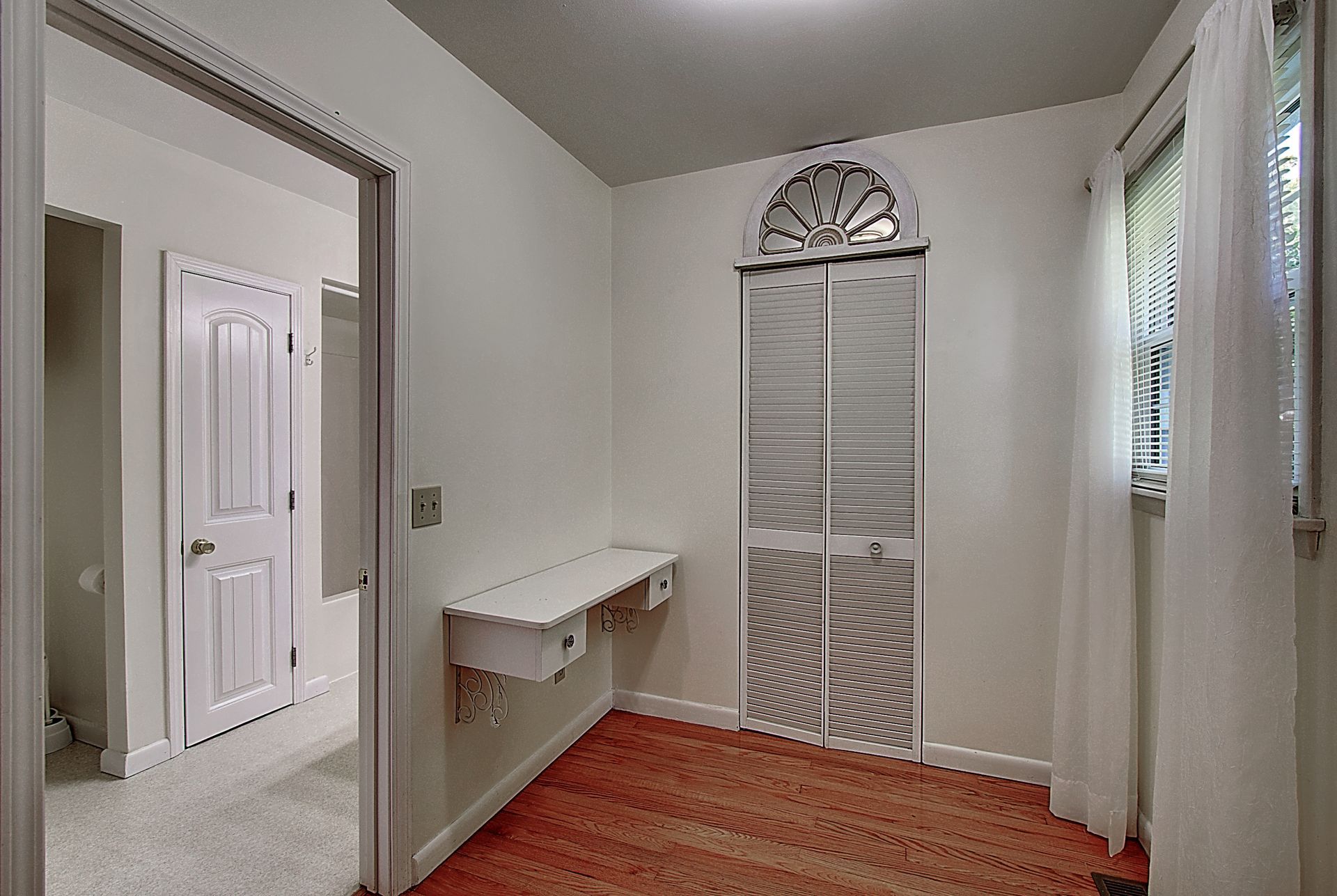 A room with a desk and a window in it.