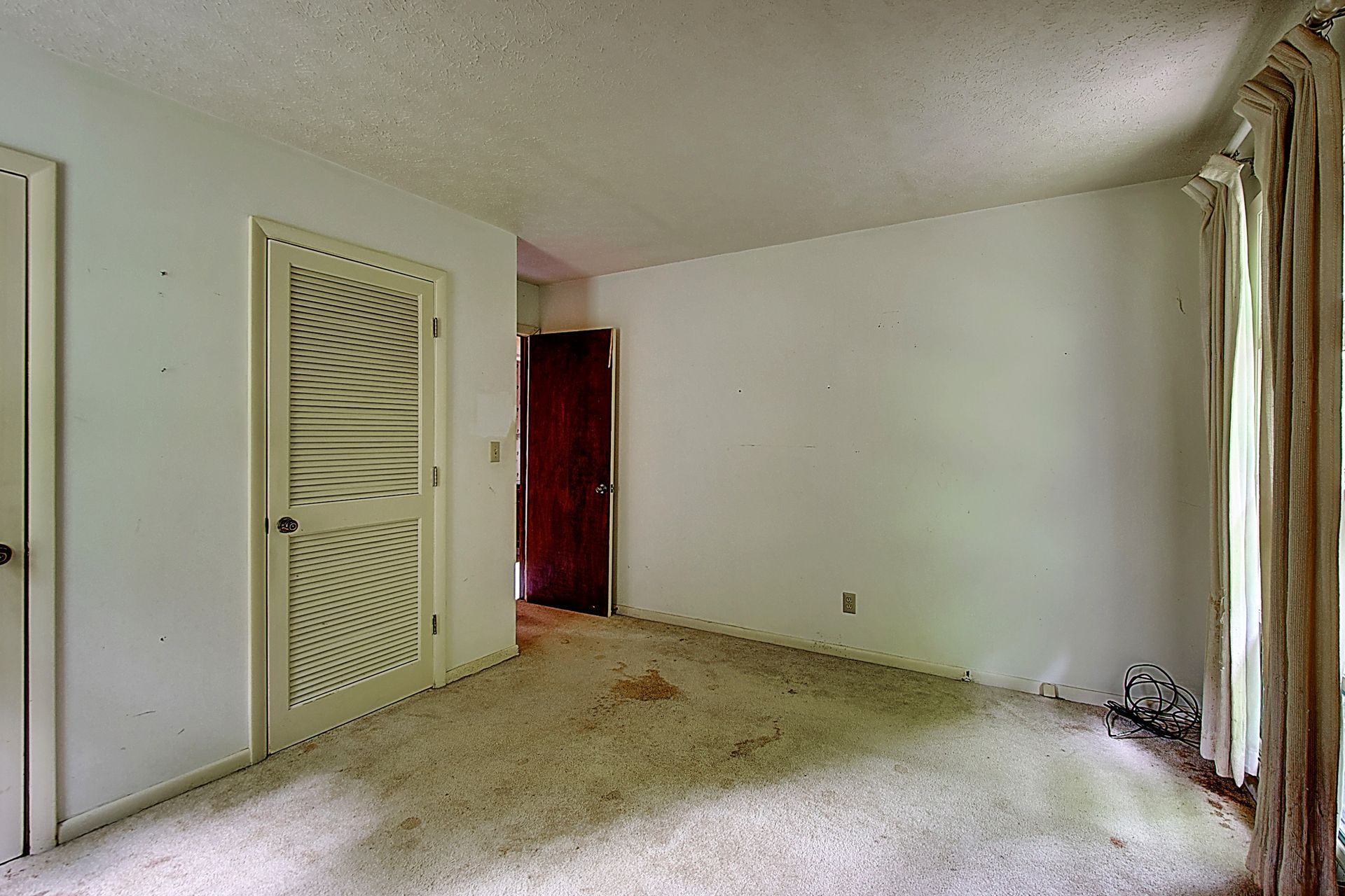 An empty room with white walls and a carpeted floor.