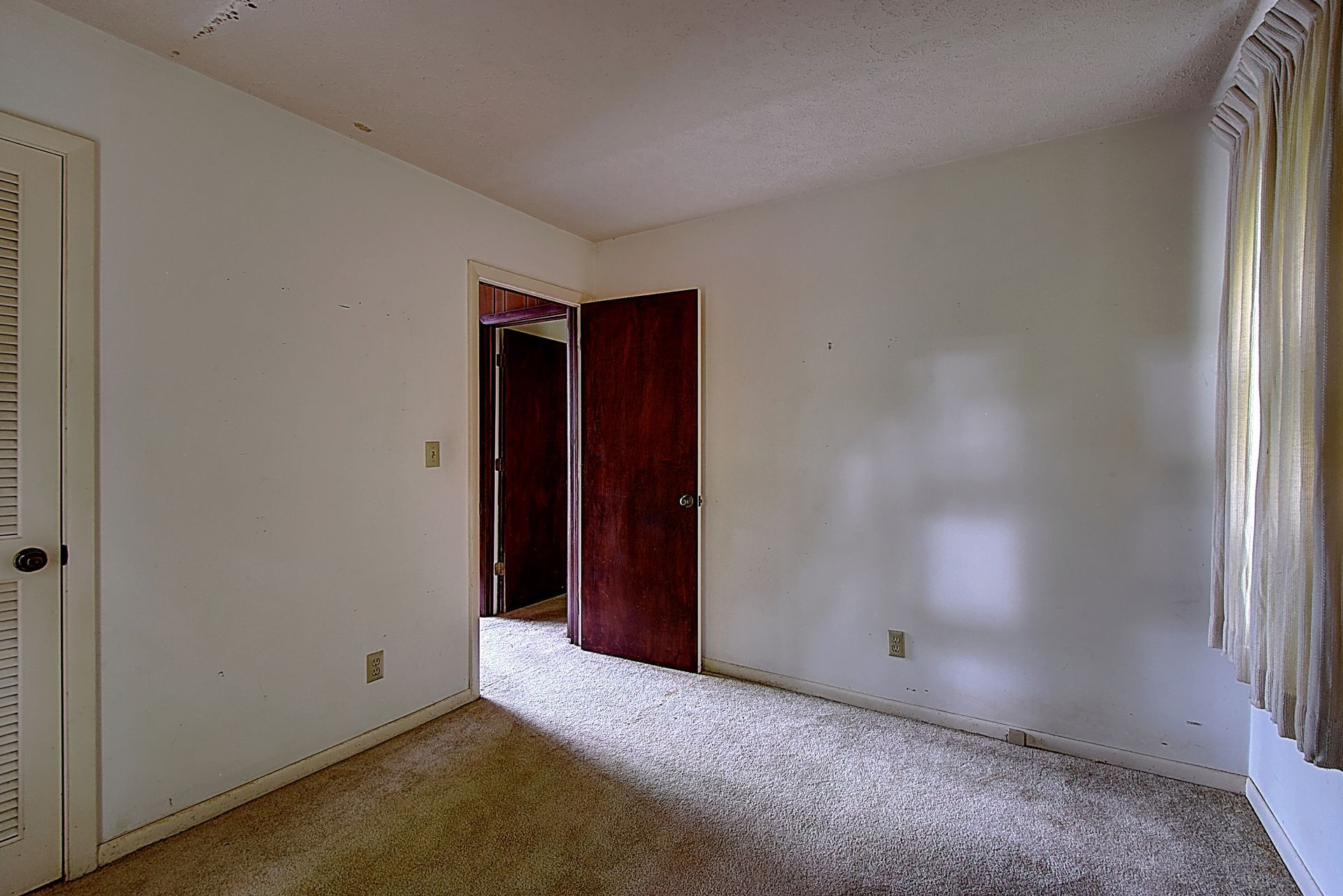 An empty bedroom with a carpeted floor and white walls.