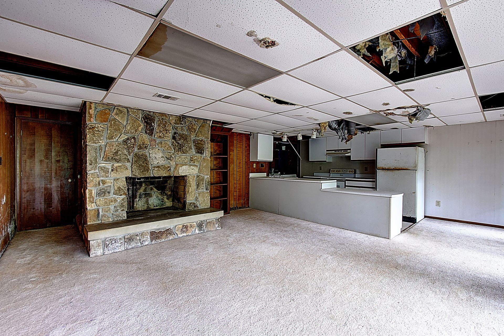 An empty room with a fireplace and a kitchen