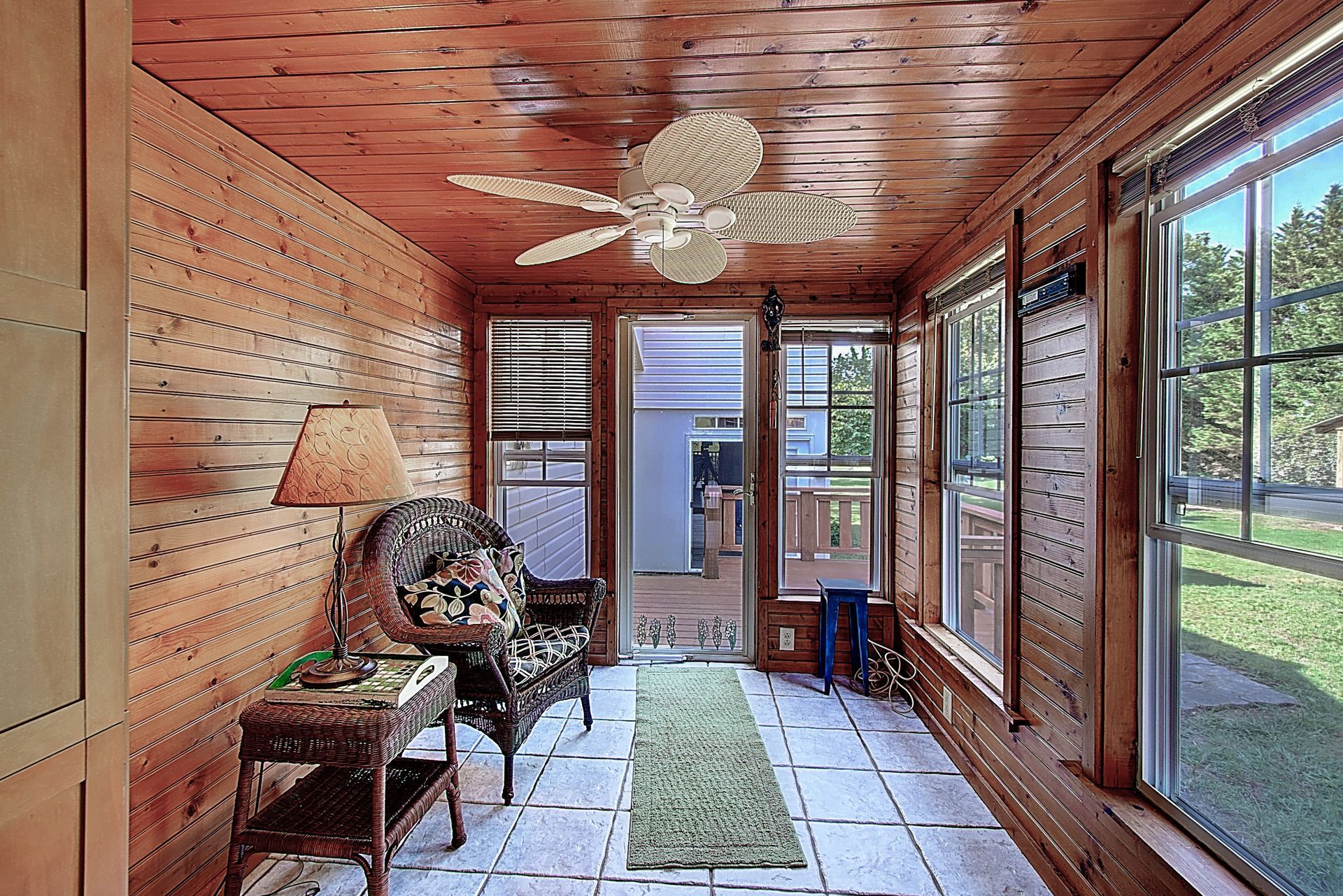 A sun room with a ceiling fan and lots of windows