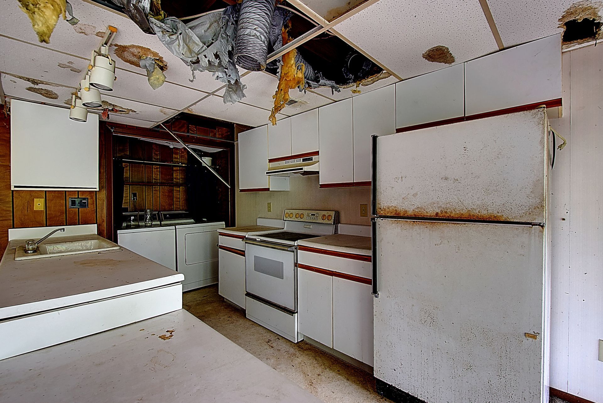 A kitchen with white cabinets and a rusty refrigerator