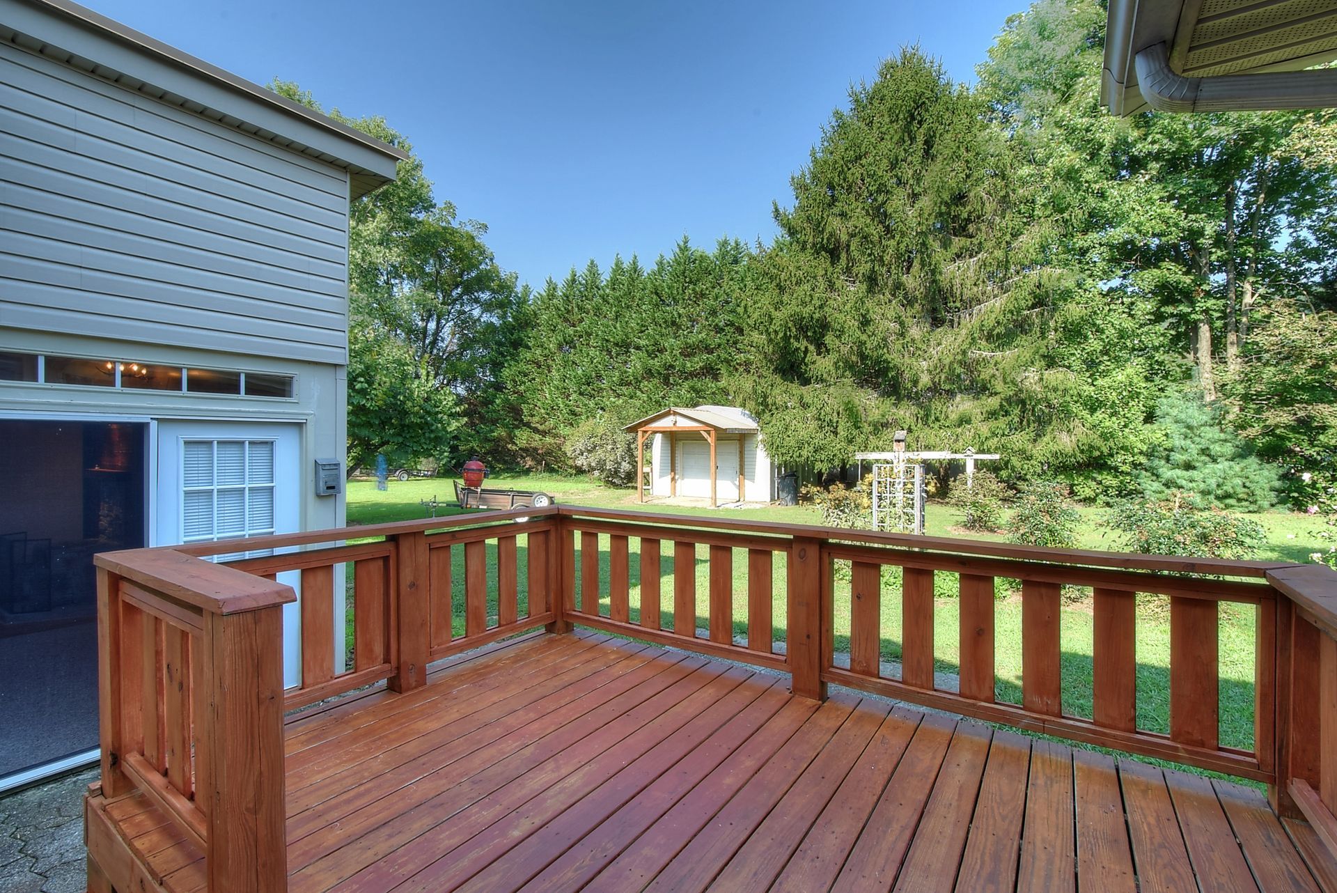 A wooden deck with a fence and a house in the background