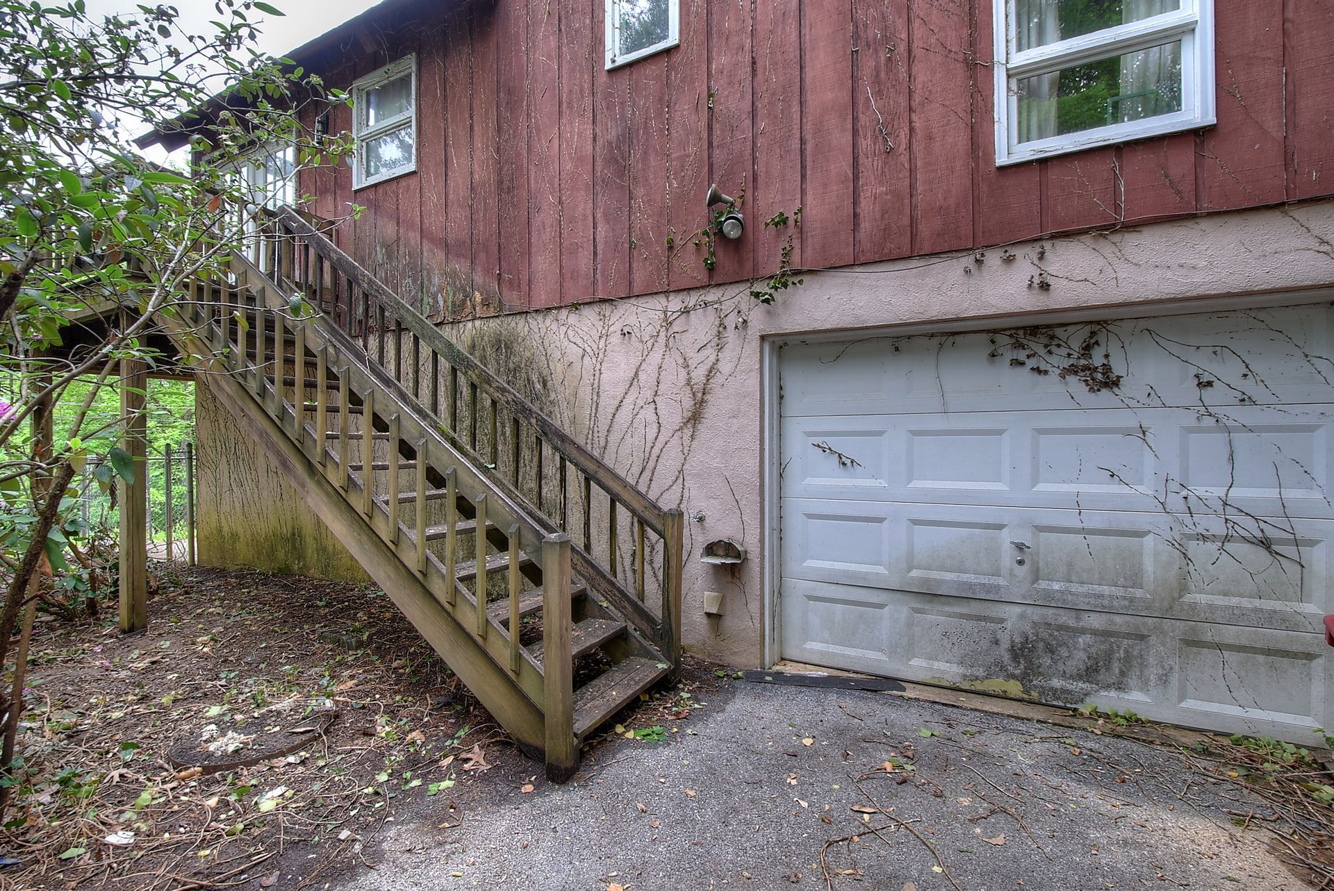 A wooden staircase leading up to a garage next to a red house.