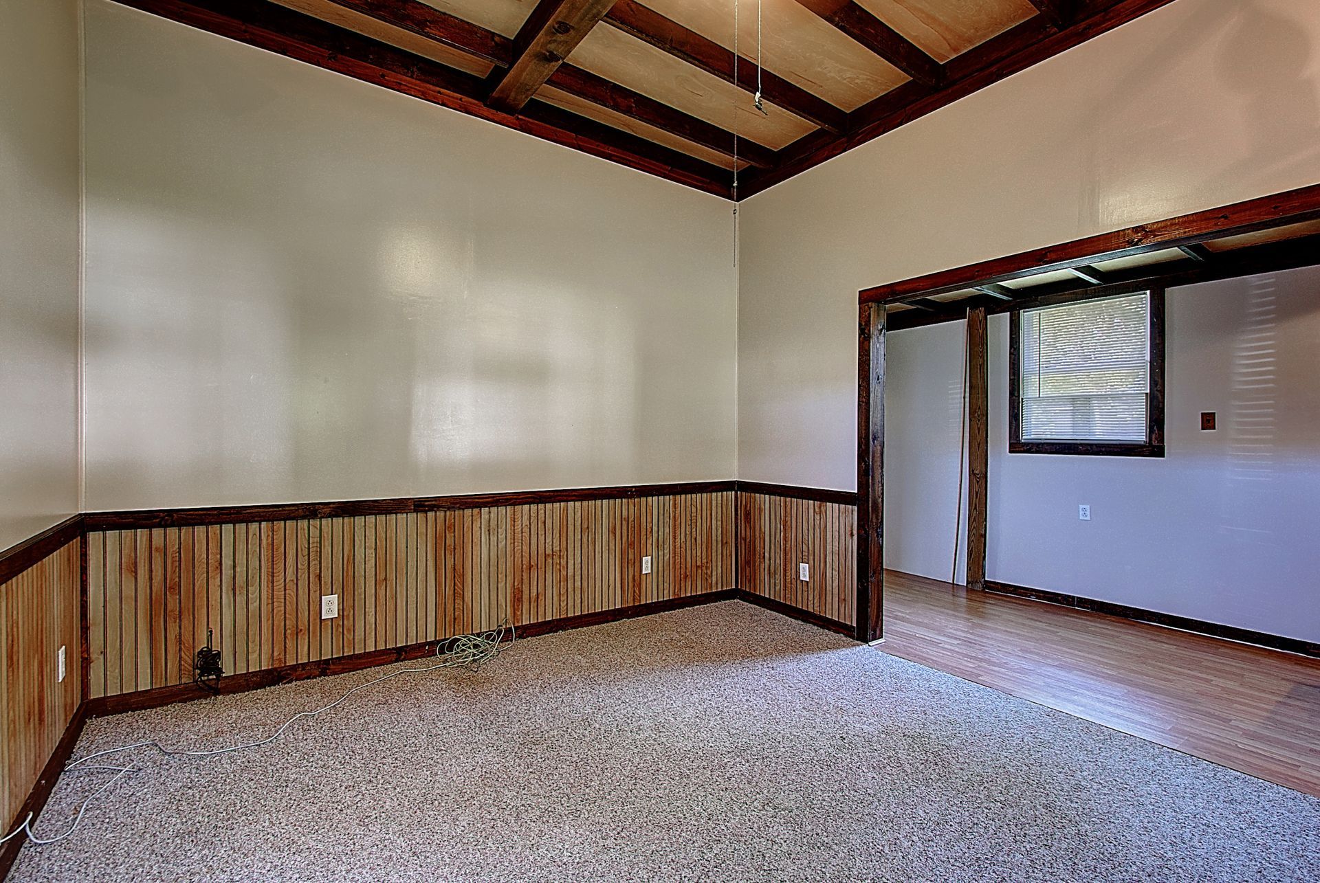 An empty room with wood paneling and a carpeted floor