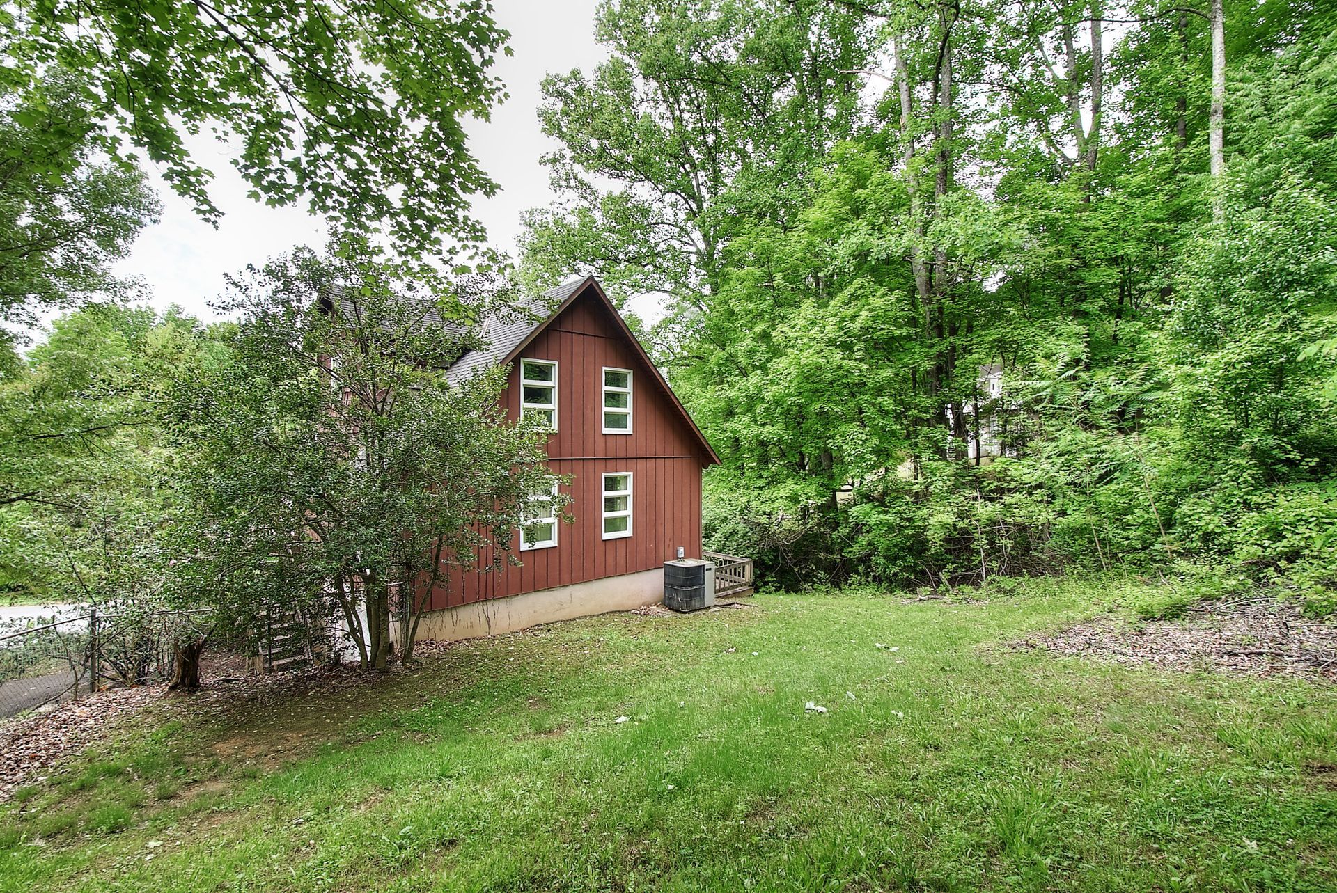 A red barn is sitting in the middle of a grassy field surrounded by trees.